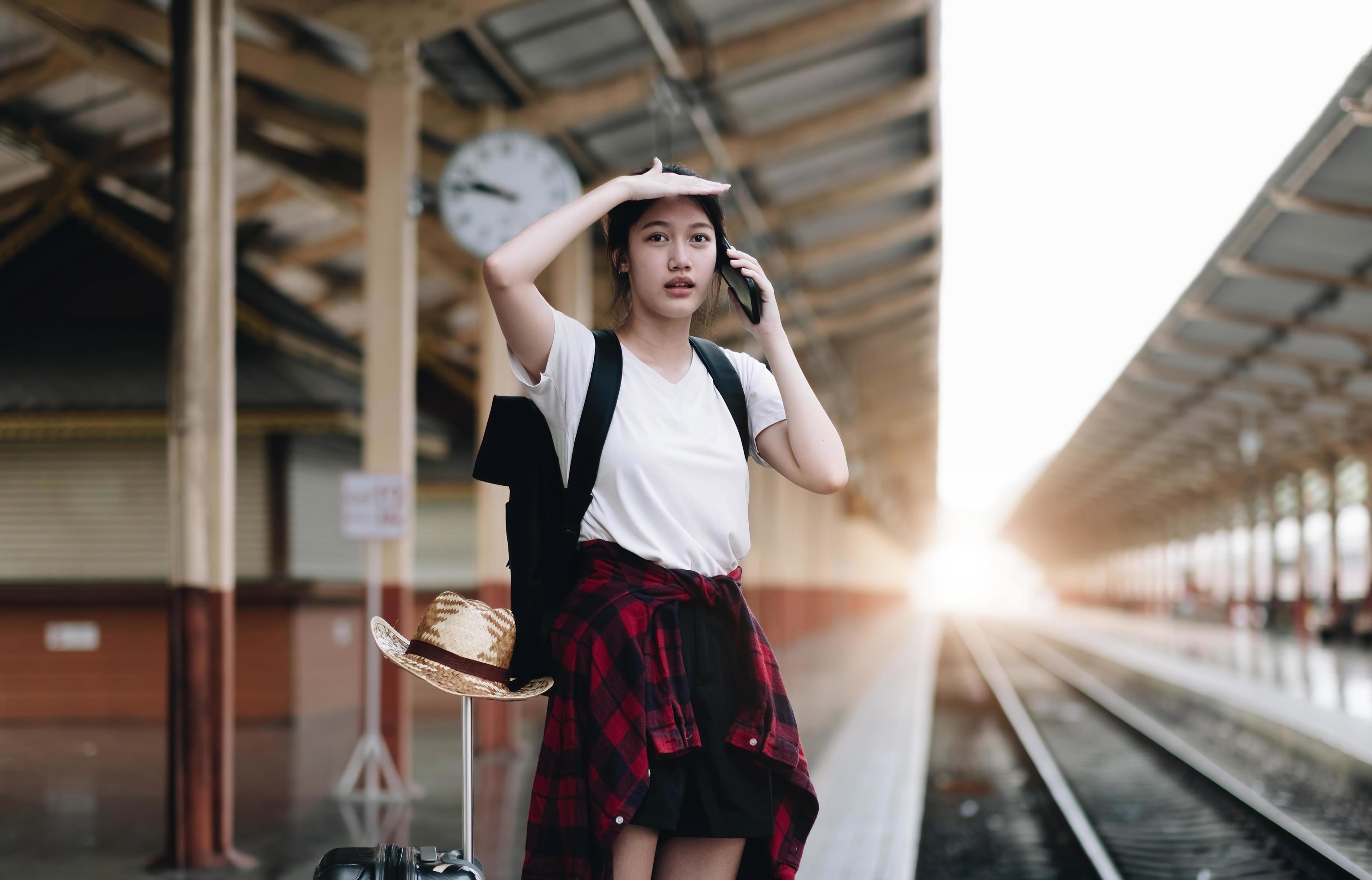 Young traveler woman looking for friend planning trip at train station. Summer and travel lifestyle concept Stock Free