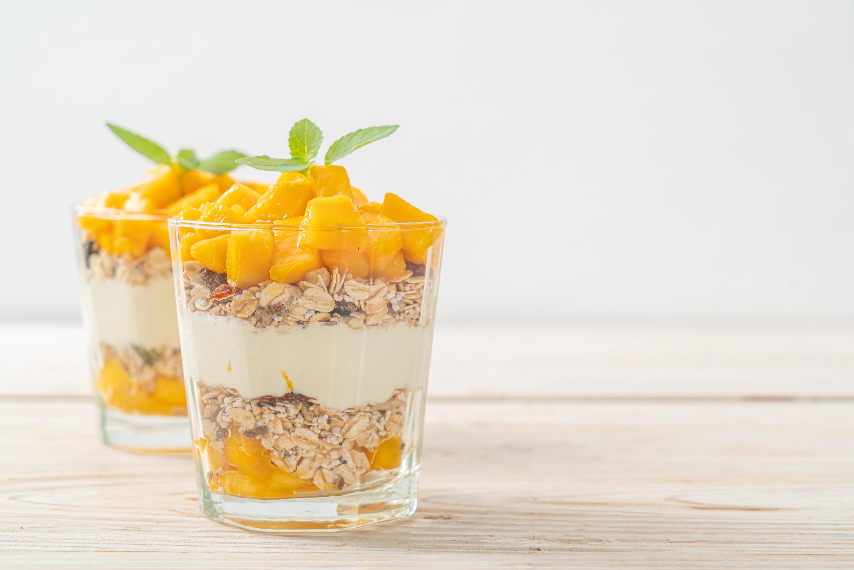 Fresh mango yogurt with granola in glass – healthy food style Stock Free