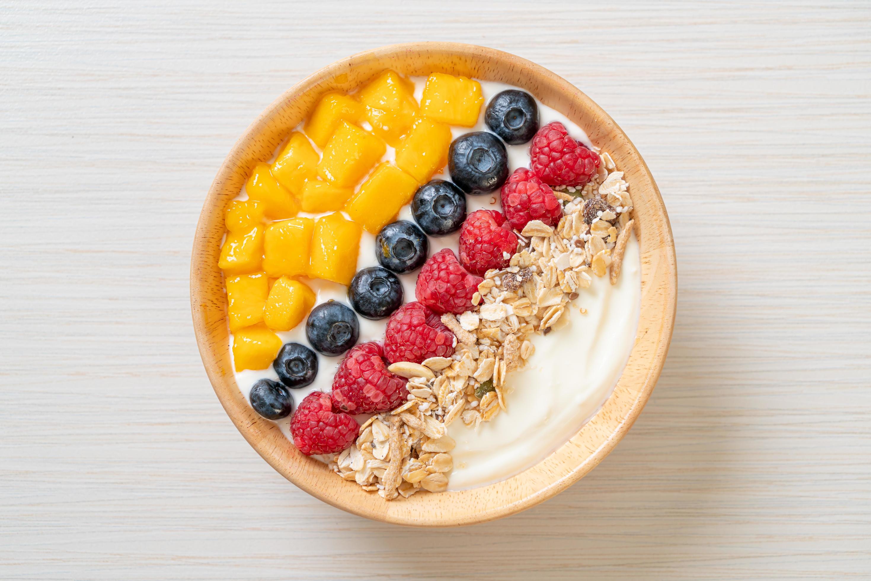 Homemade yogurt bowl with raspberry, blueberry, mango, and granola – healthy food style Stock Free