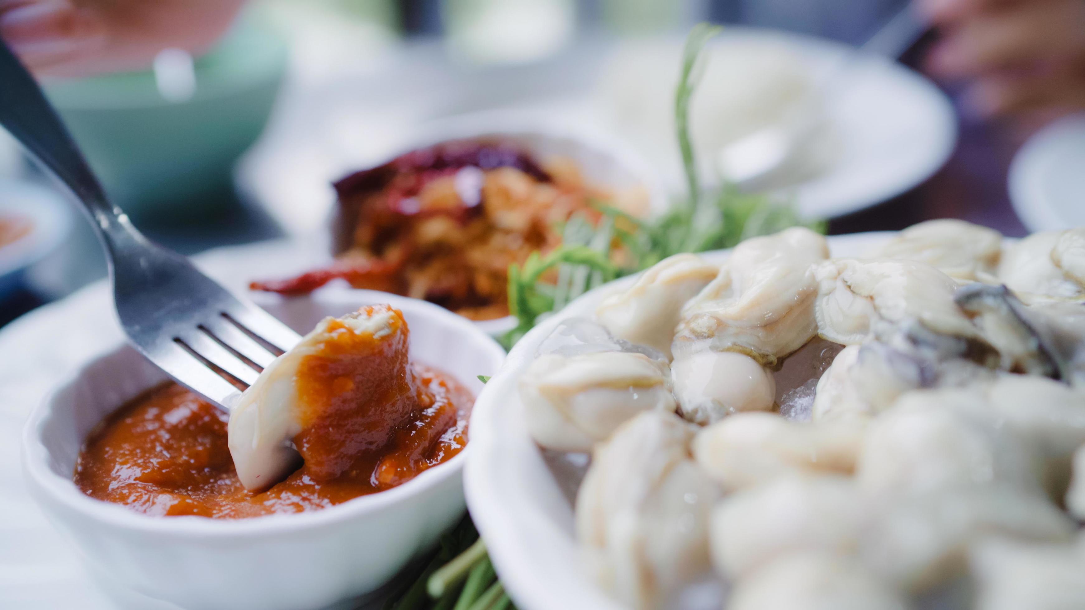 Young Asian woman eating oyster seafood in restaurant, teenager female feeling happy eating food. Women eating seafood concept. Stock Free