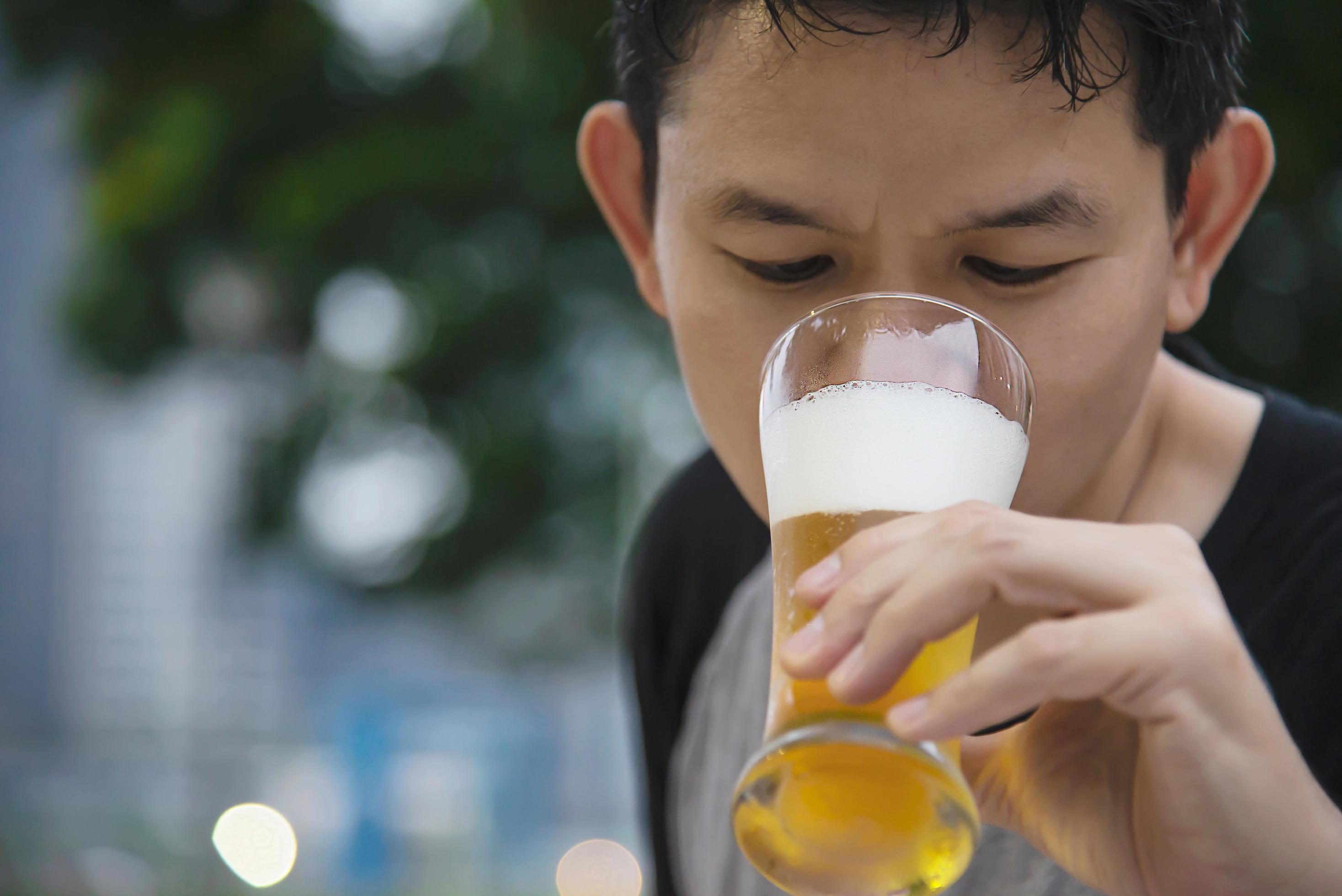 Asian man drinking beer in green garden restaurant – people relax enjoy soft drink lifestyle concept Stock Free