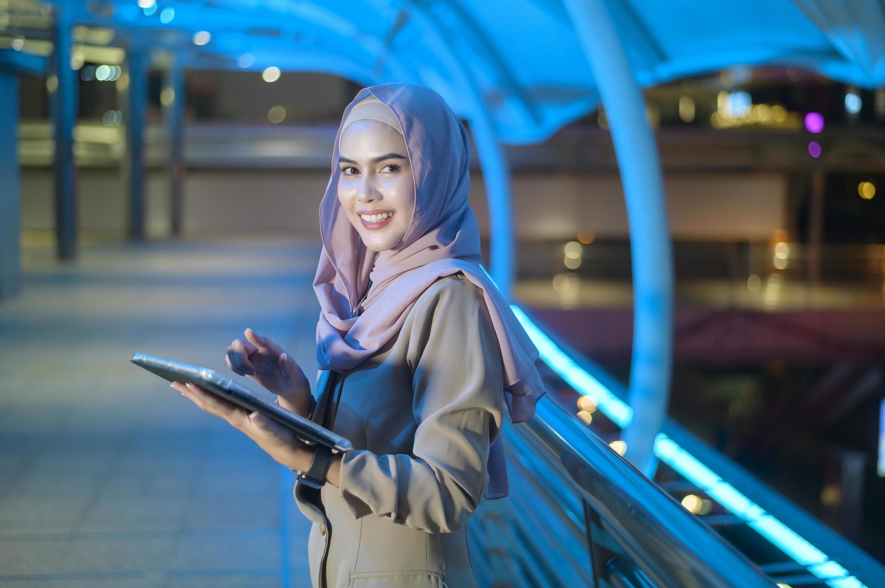 A young Muslim Businesswoman is using tablet computer in modern City at night , Business technology lifestyle concept Stock Free