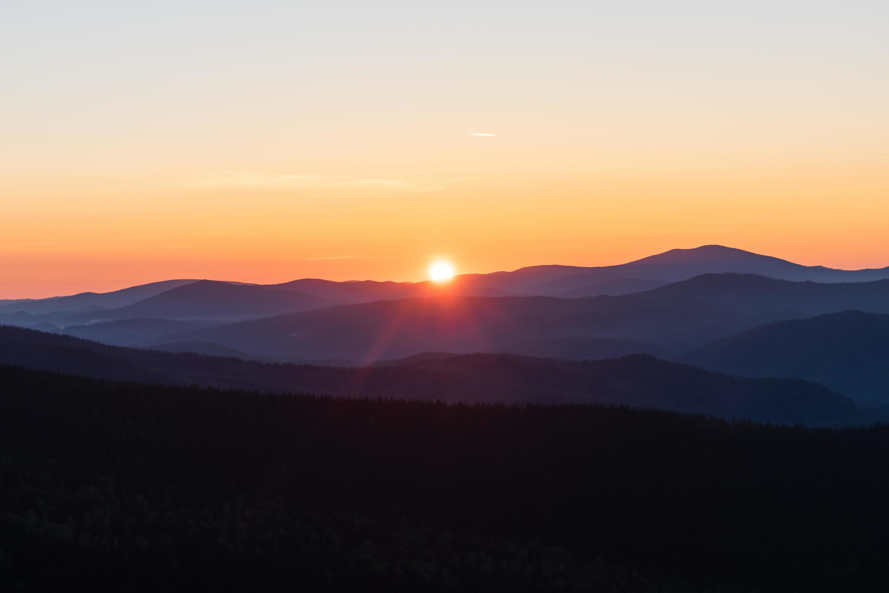 Beautiful and bright sunrise in the mountains. The sun’s rays make their way from the tops of the misty mountains Stock Free