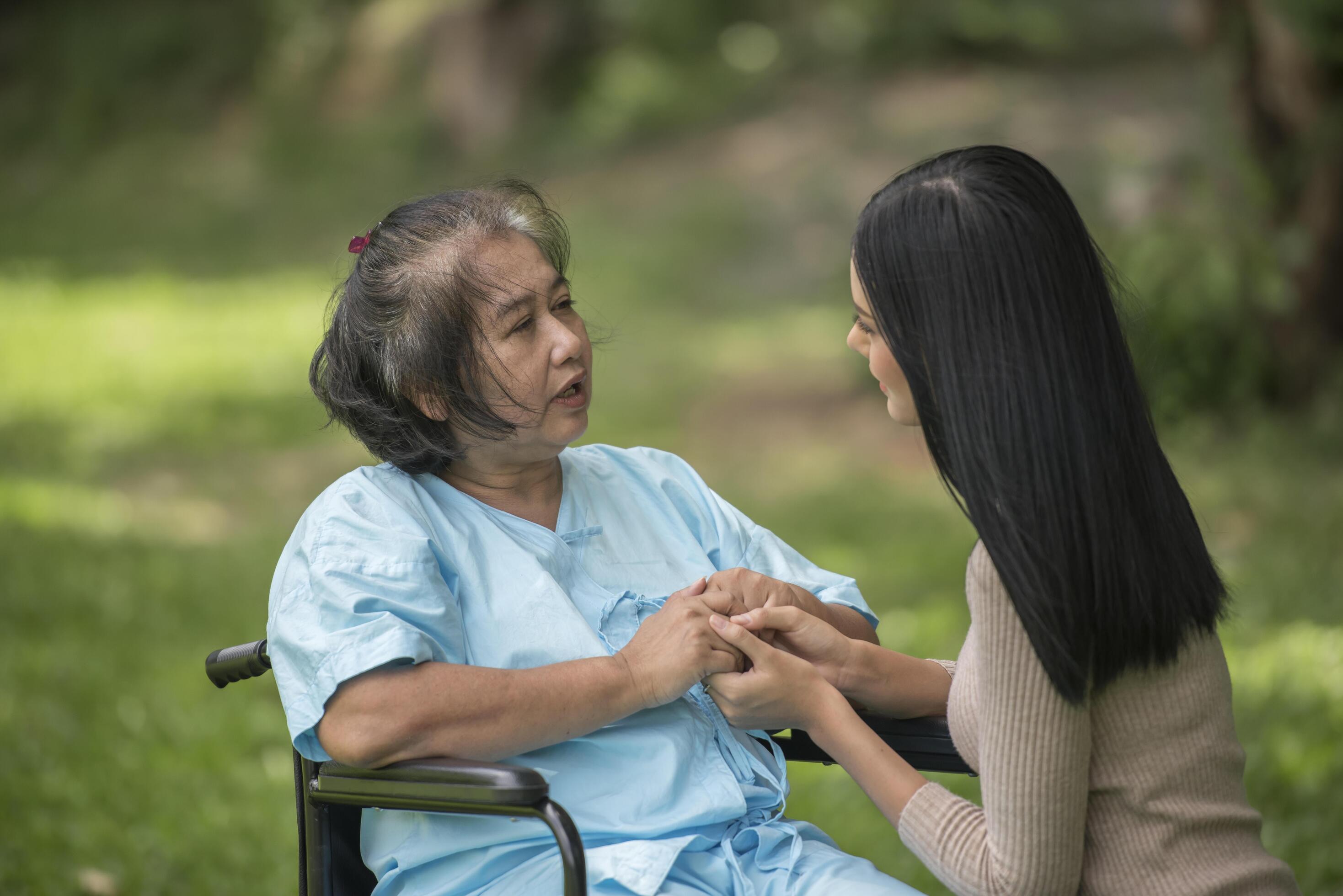 Granddaughter talking with her grandmother sitting on wheelchair, cheerful concept, happy family Stock Free