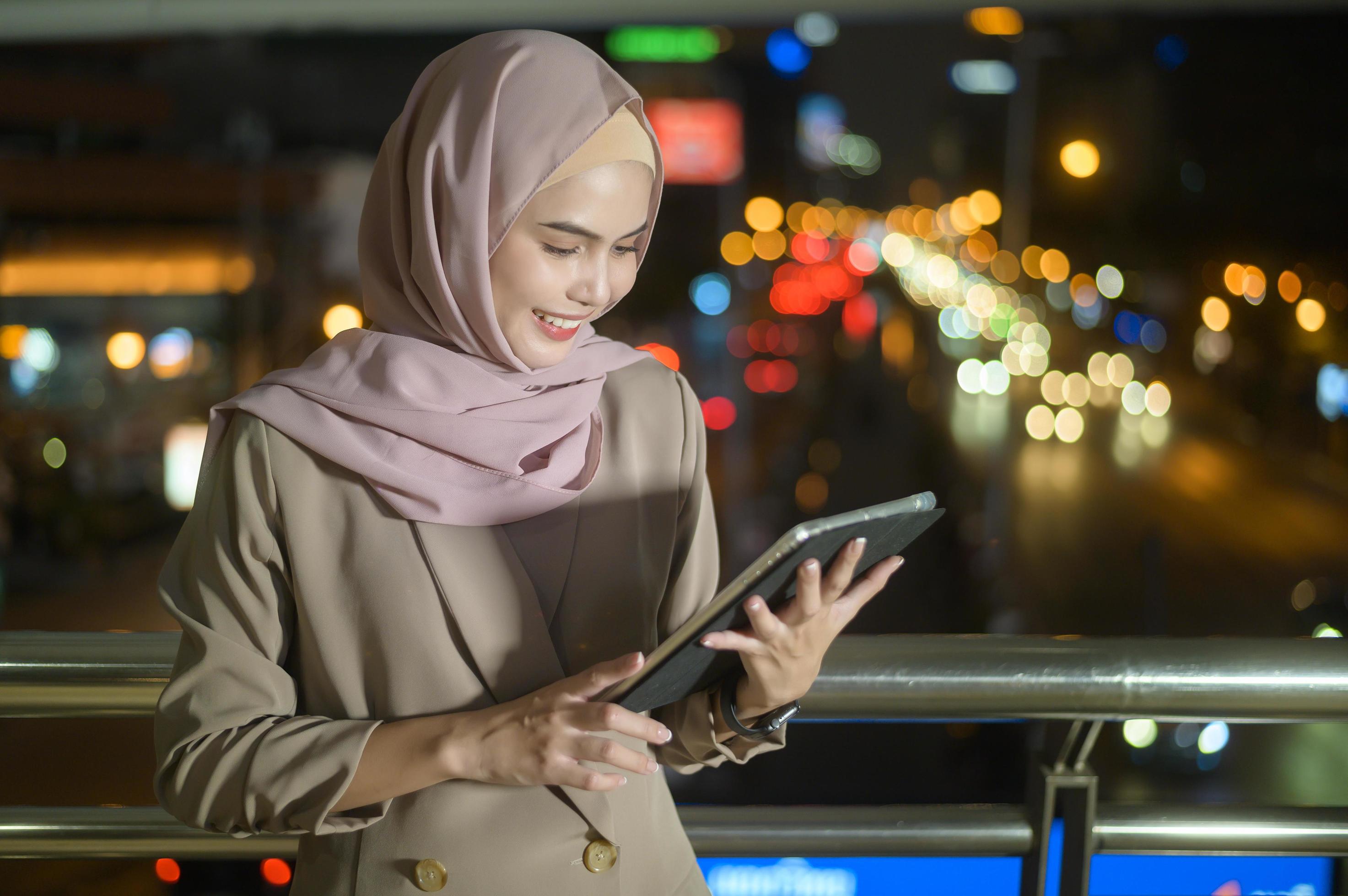 A young Muslim Businesswoman is using tablet computer in modern City at night , Business technology lifestyle concept Stock Free