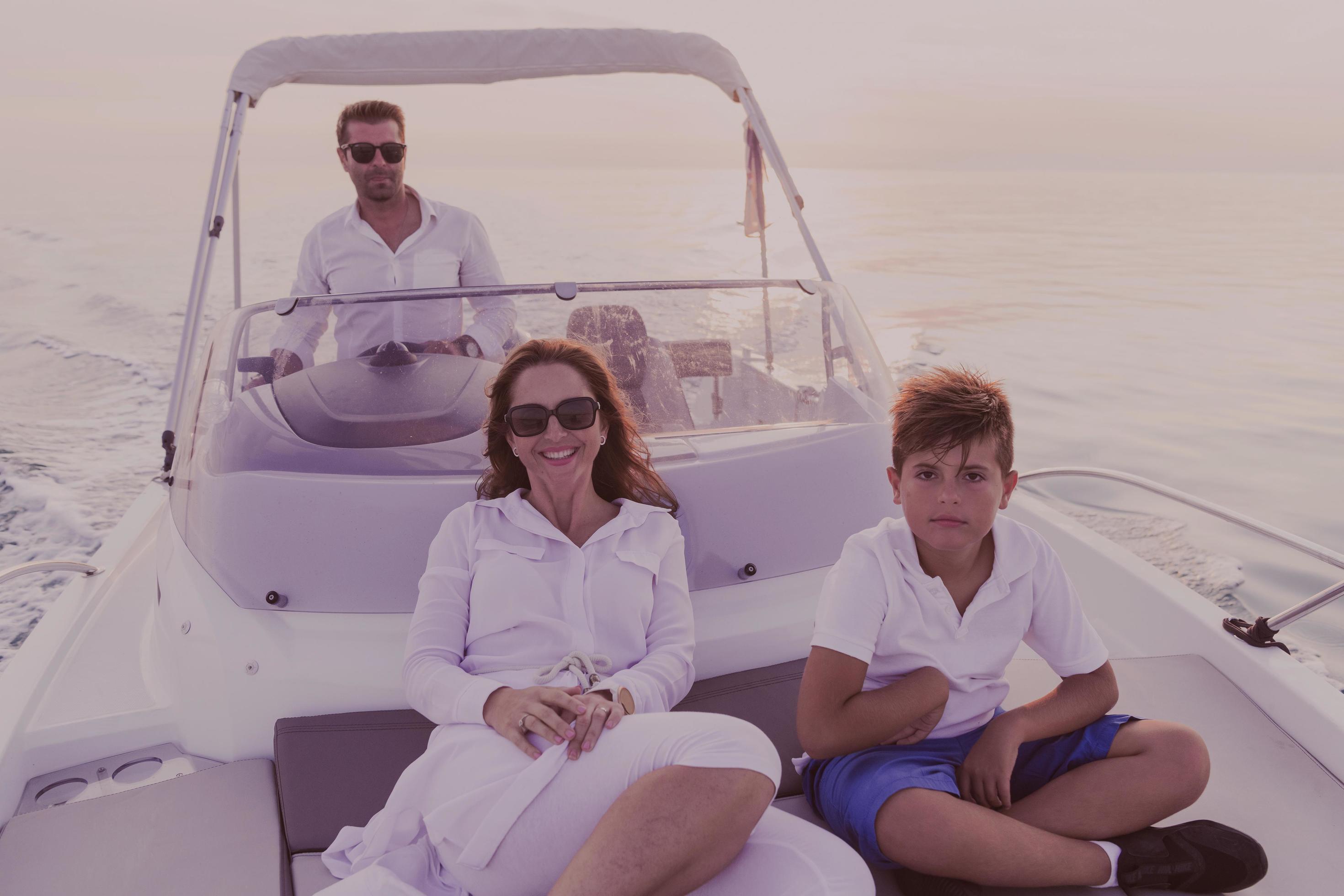 A senior couple in casual outfits with their son enjoy while riding a boat at sea at sunset. The concept of a happy family. Selective focus Stock Free