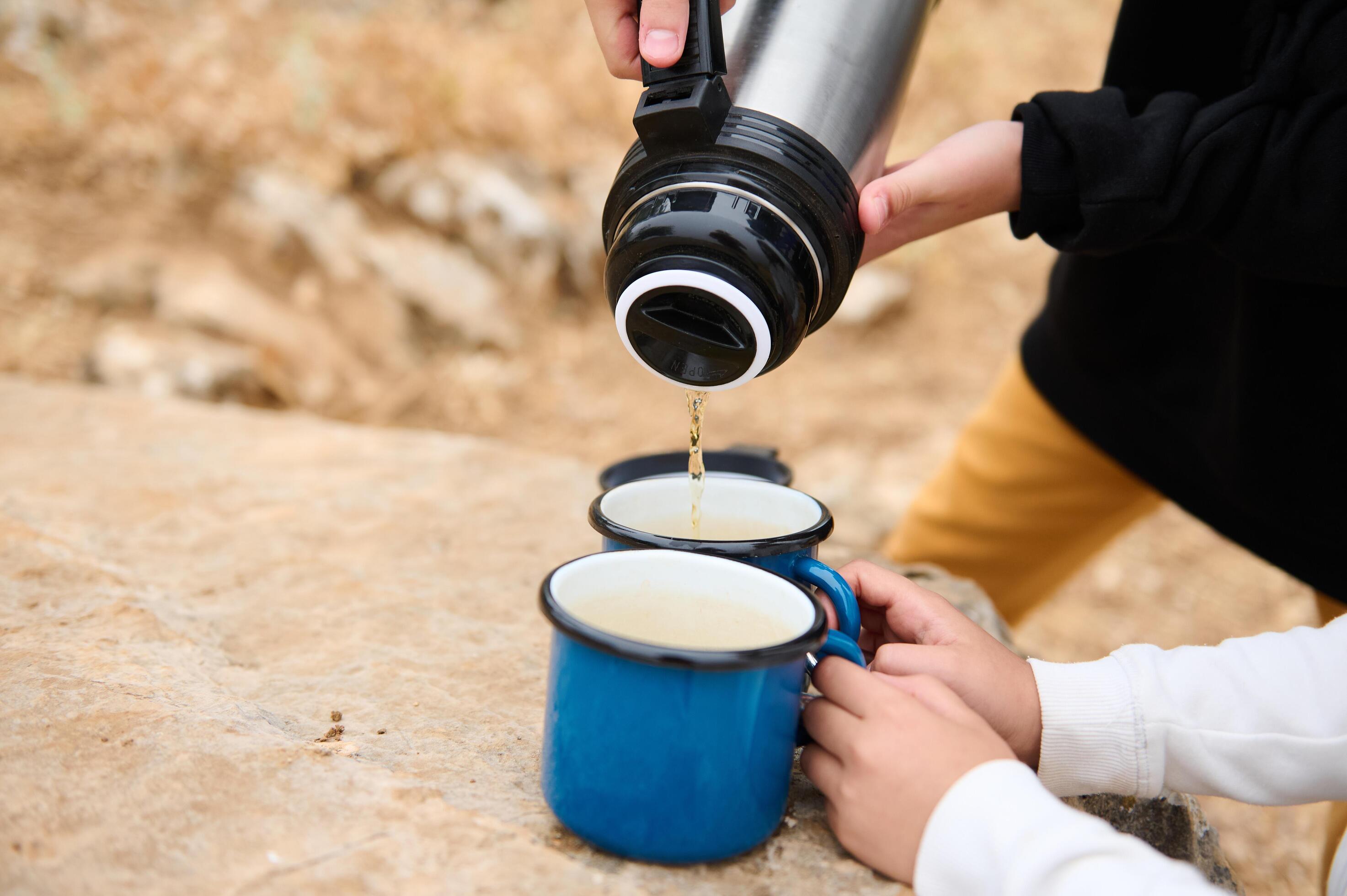 Family pouring hot drink into cups during an outdoor adventure Stock Free