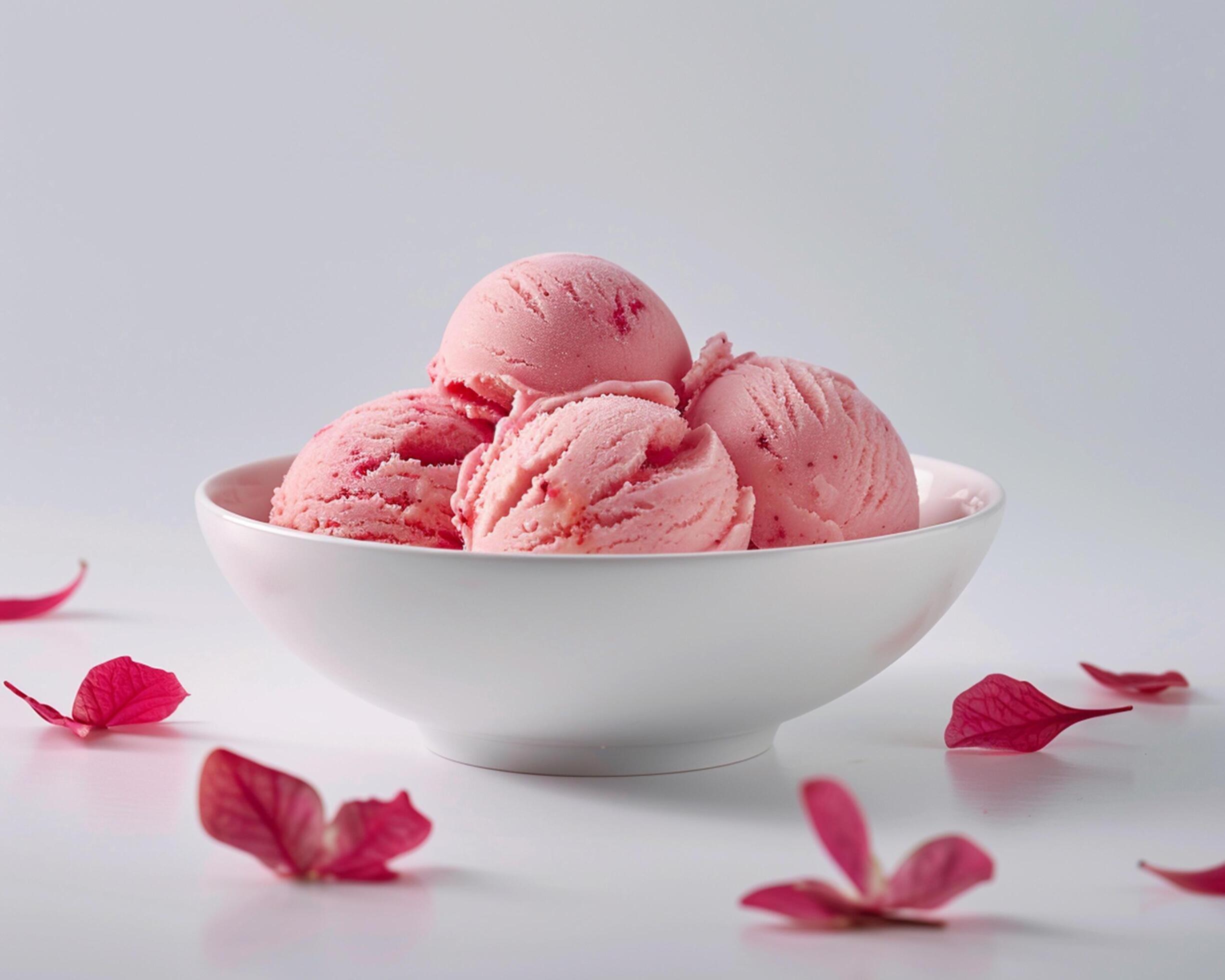 A bowl of pink ice cream with petals scattered around it Stock Free