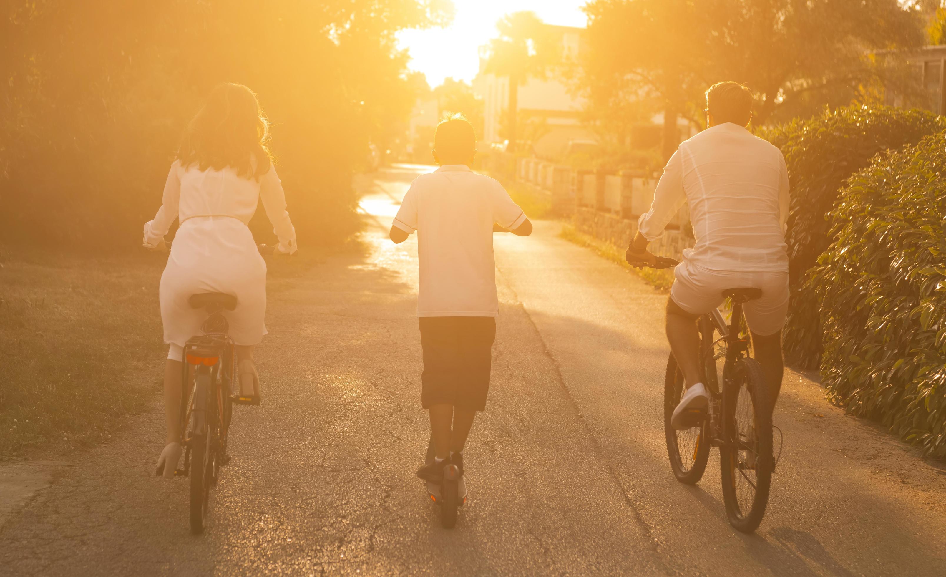 Happy family enjoying a beautiful morning together, parents riding a bike and their son riding an electric scooter. Selective focus Stock Free