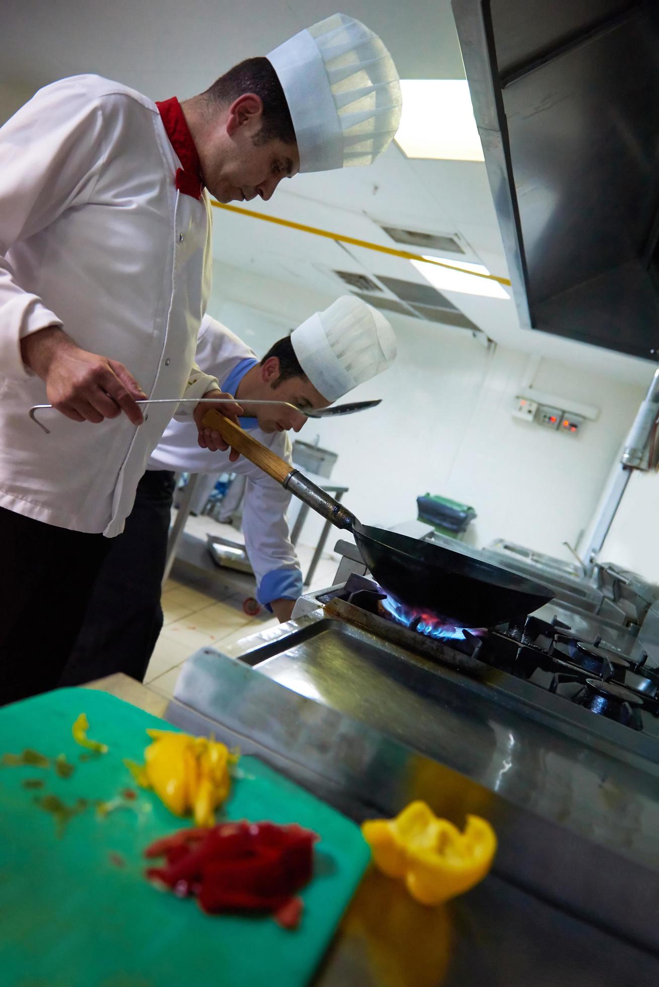 chef in hotel kitchen prepare food with fire Stock Free