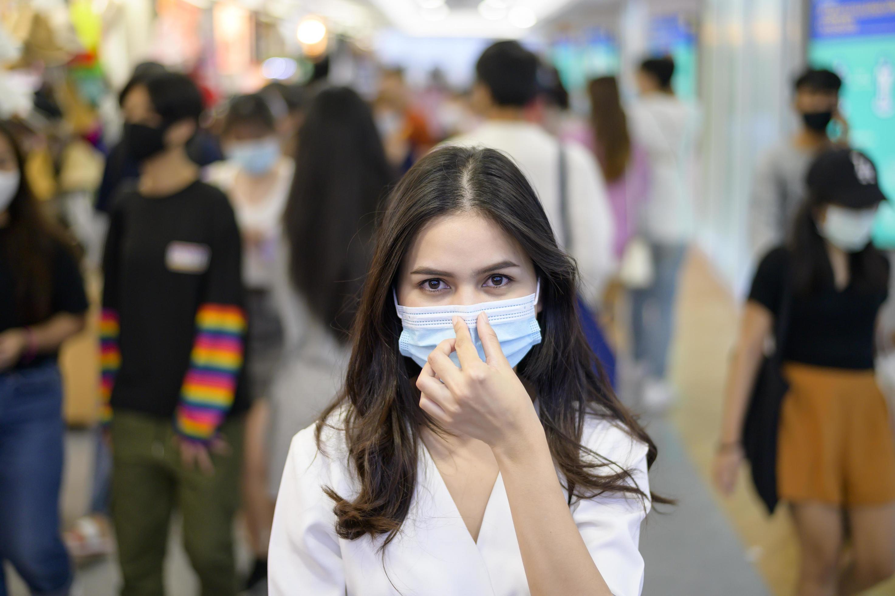 A woman is wearing protective mask on Street with Crowded people while covid-19 pandemic, Coronavirus protection , safety lifestyles concept Stock Free