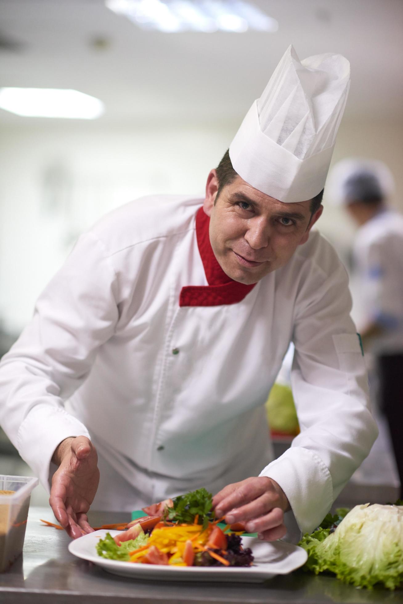 chef in hotel kitchen preparing and decorating food Stock Free