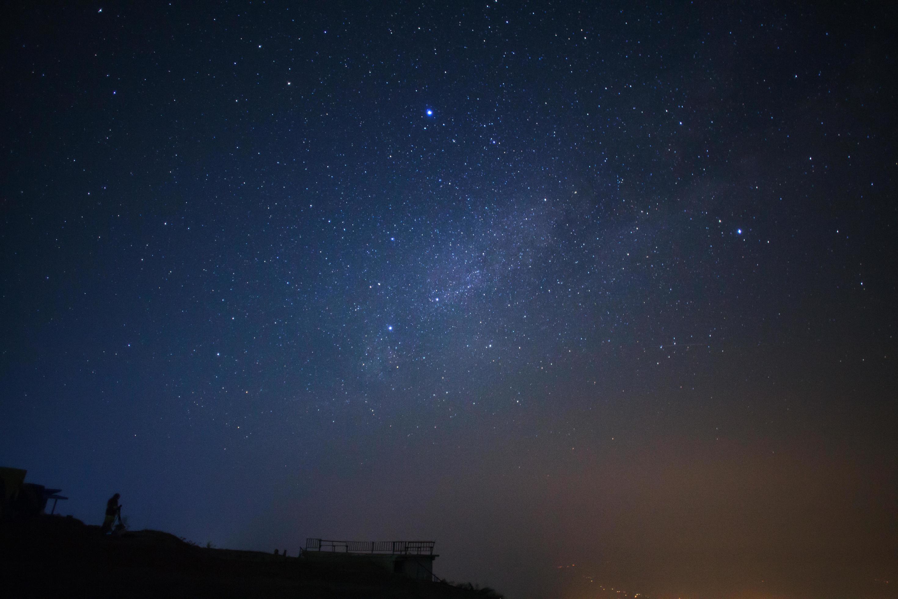 Silhouette of a standing man with telescope or camera watching the wilky way galaxy Stock Free