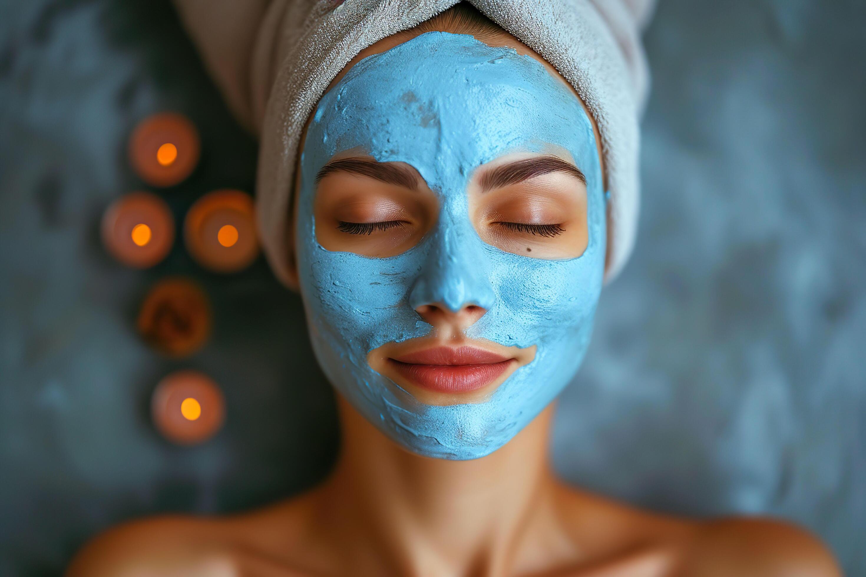 Beautiful young woman with blue clay facial mask on her face. Stock Free