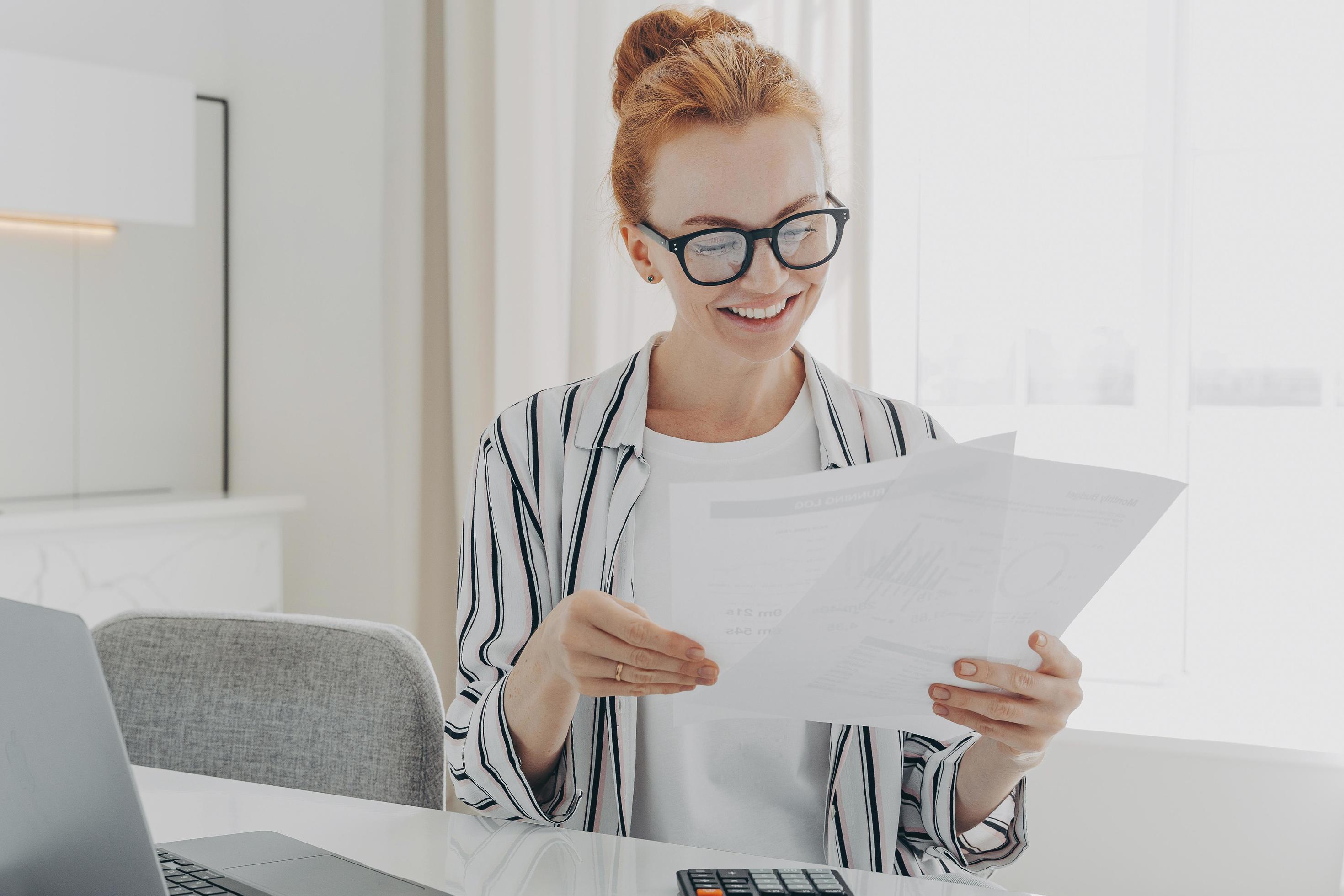 Happy smiling caucasian woman reading good news in financial documents while managing family budget Stock Free