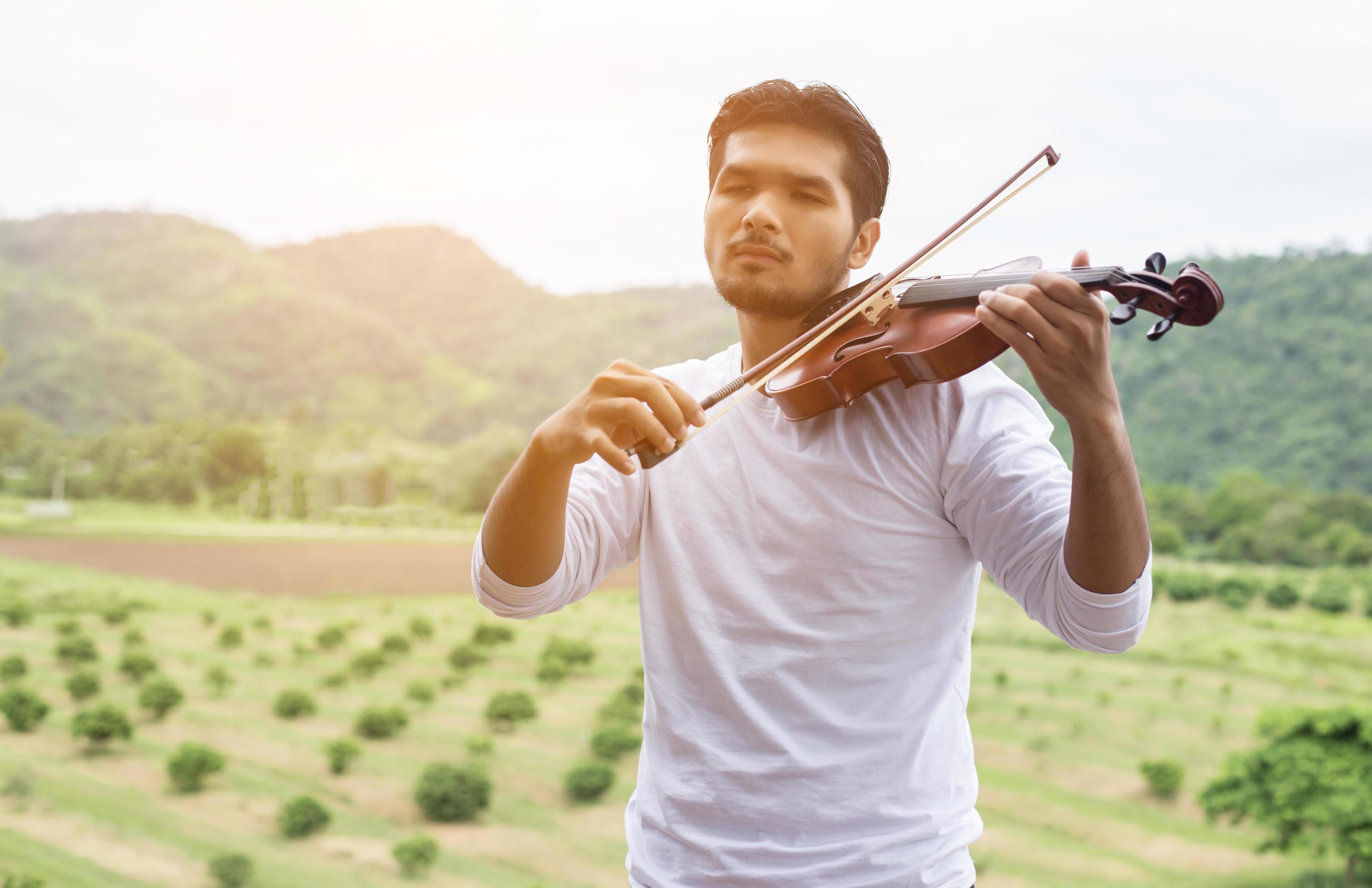 Young hipster musician man playing violin in the nature outdoor lifestyle behind mountain. Stock Free