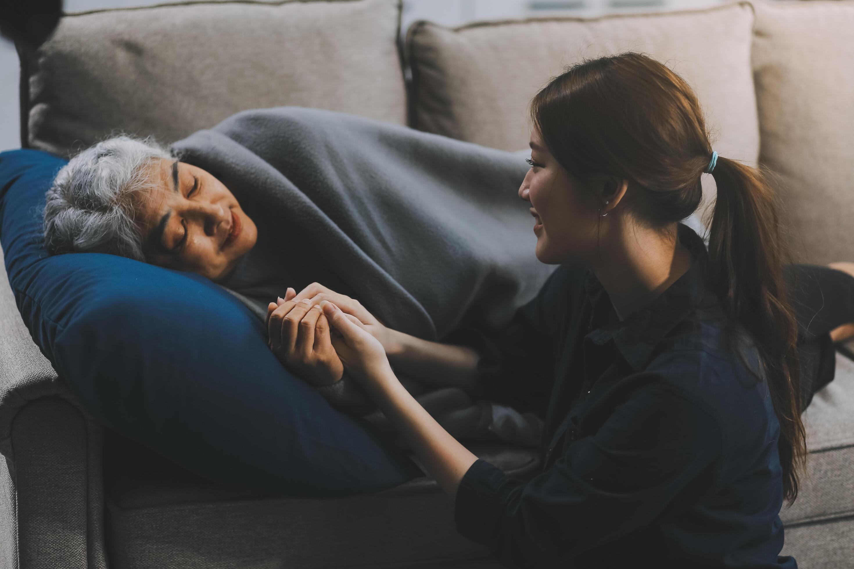 happy family Granddaughter takes care of her grandmother with warm cloths sitting on the sofa. Stock Free