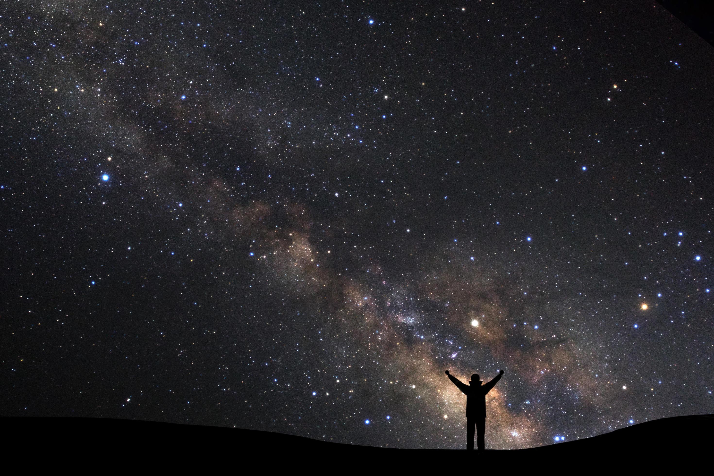 landscape with milky way, Night sky with stars and silhouette of a standing sporty man with raised up arms on high mountain. Stock Free