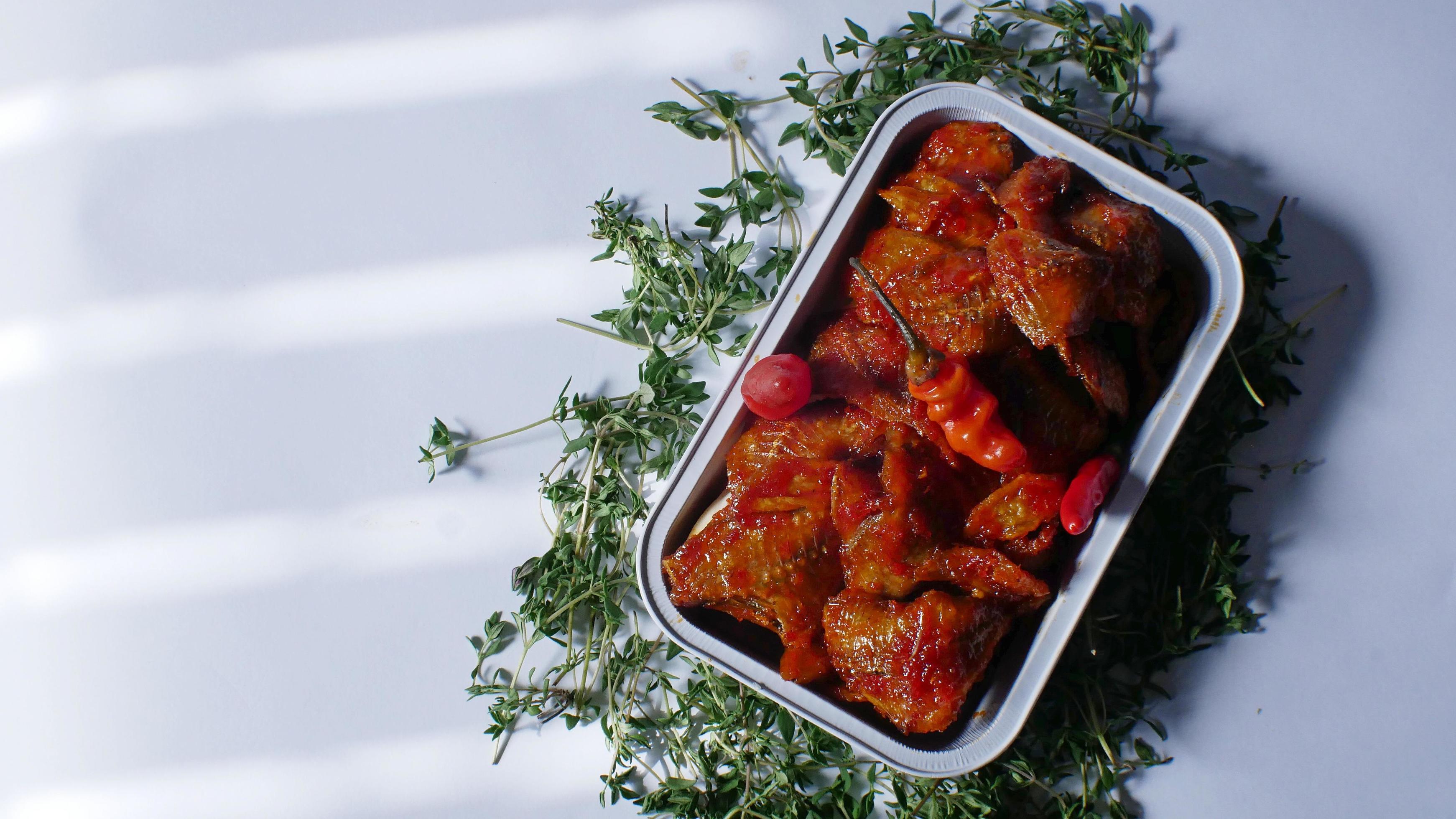 salted fish with spicy sweet and sour seasoning Indonesian food served simply in an aluminum place with white background Stock Free