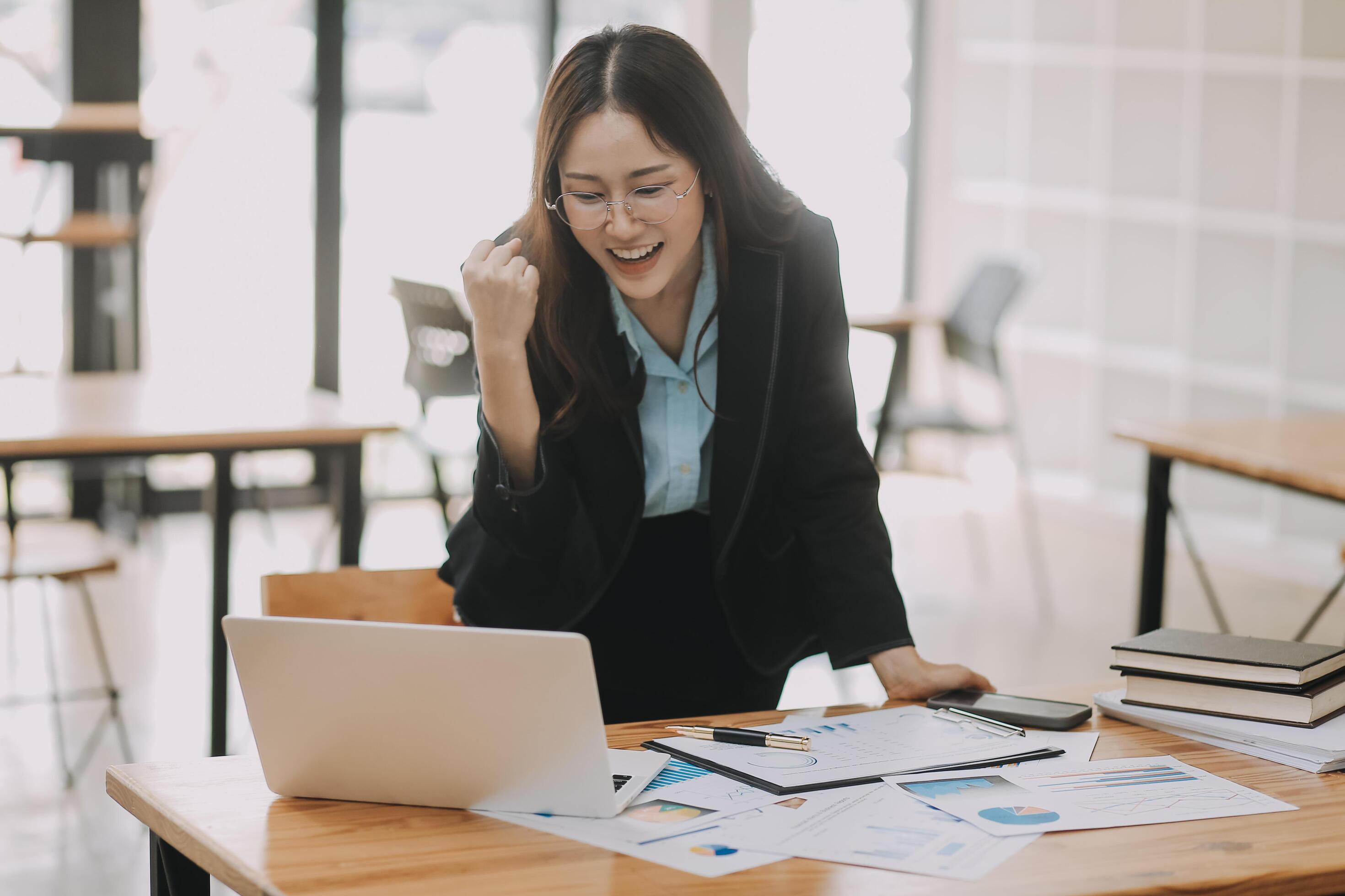 Happy young asian businesswoman sitting on her workplace in the office. Young woman working at laptop in the office. Stock Free