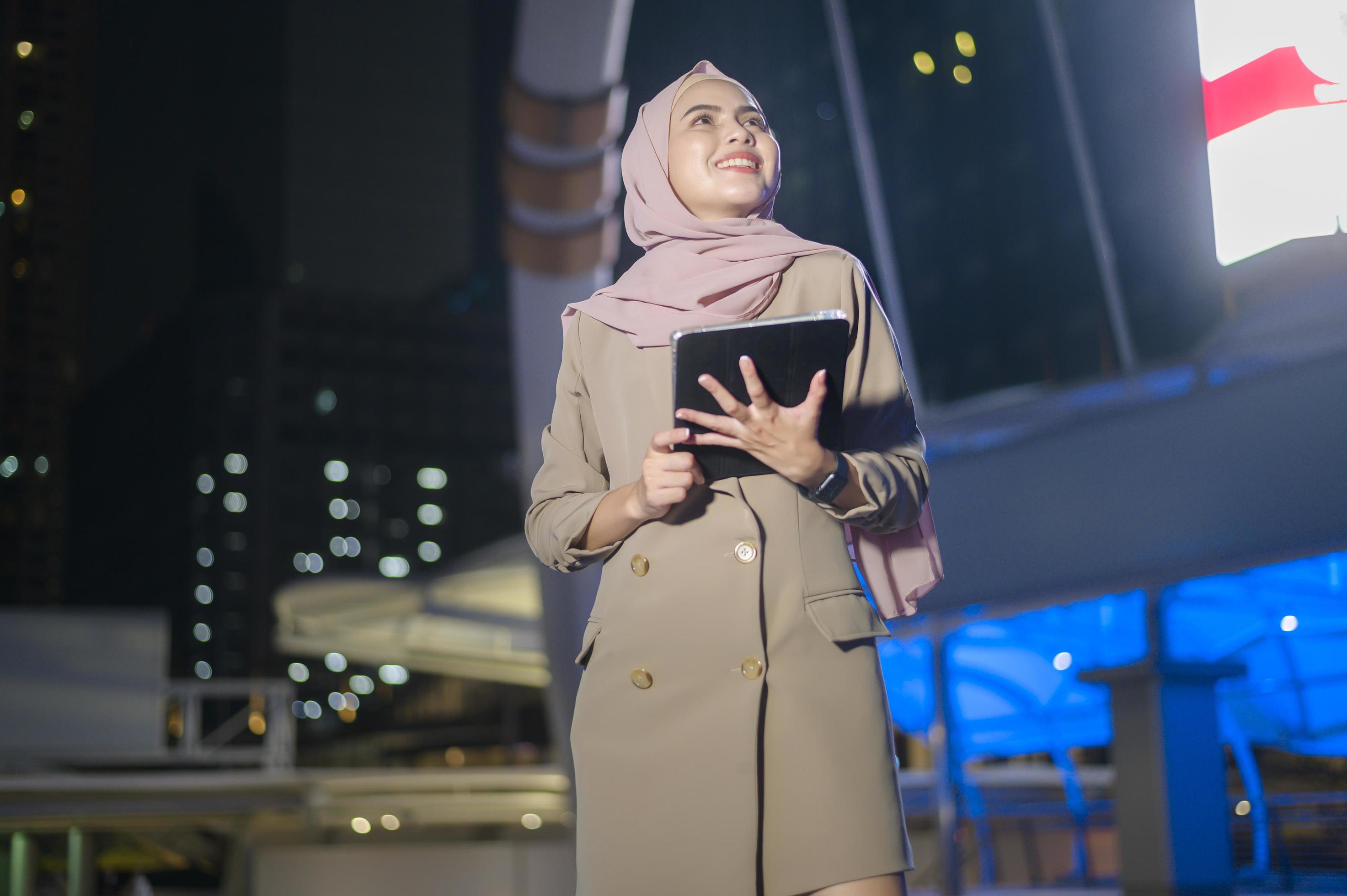 A young Muslim Businesswoman is using tablet computer in modern City at night , Business technology lifestyle concept Stock Free