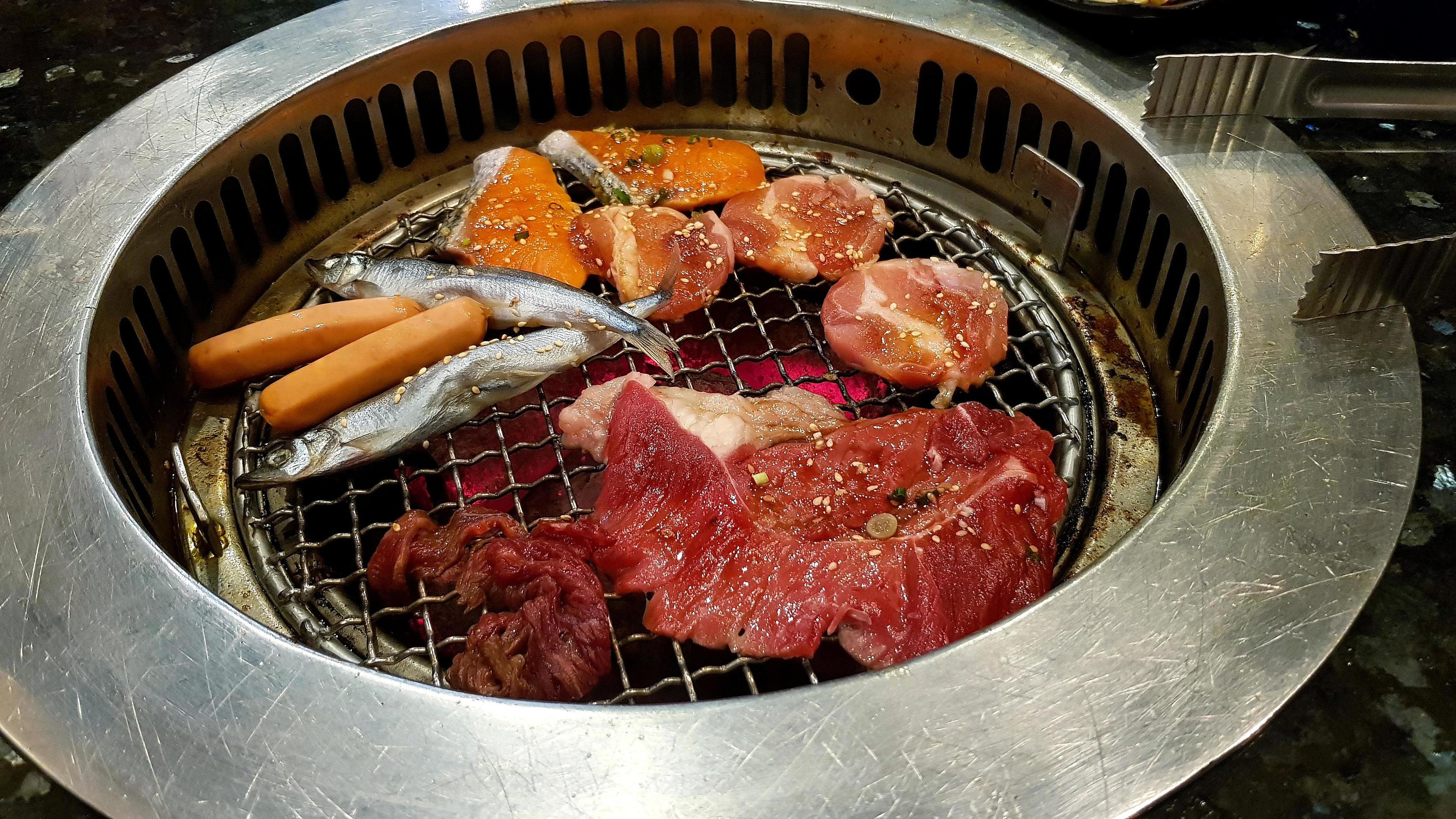 Group of barbeque meat on grilled stove with hot dog or sausages, fresh fish, salmon, pork, beef at Korean restaurant. Lunch time and eating food Stock Free