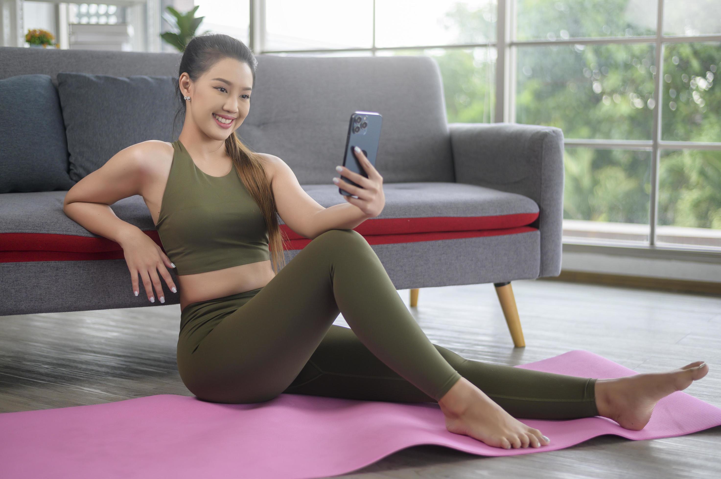 Young fitness woman in sportswear using smart phone while exercising at home, Healthy and Lifestyles. Stock Free