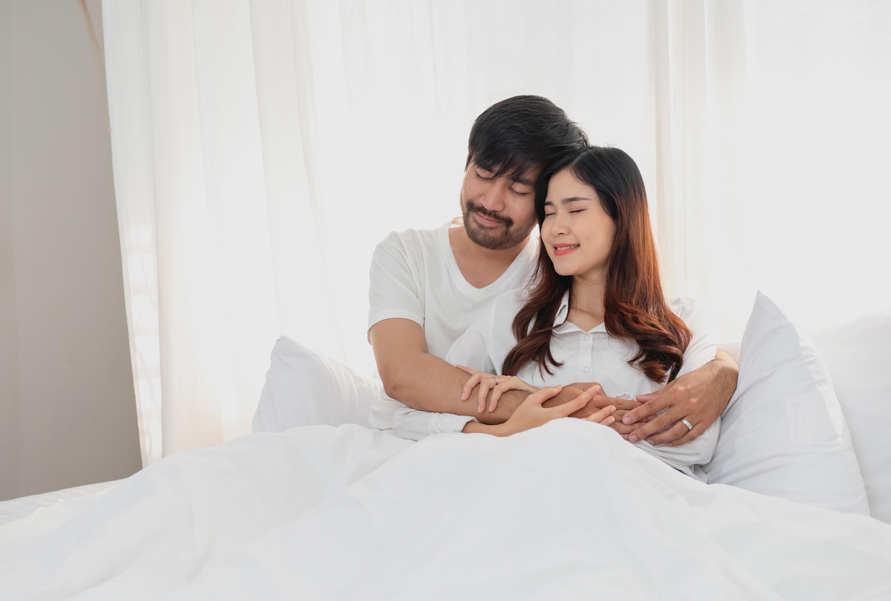 Happy young asian couple embracing, teasing, playing cheerfully in bed at home, romantic time to enhance family bonding. family concept. Stock Free