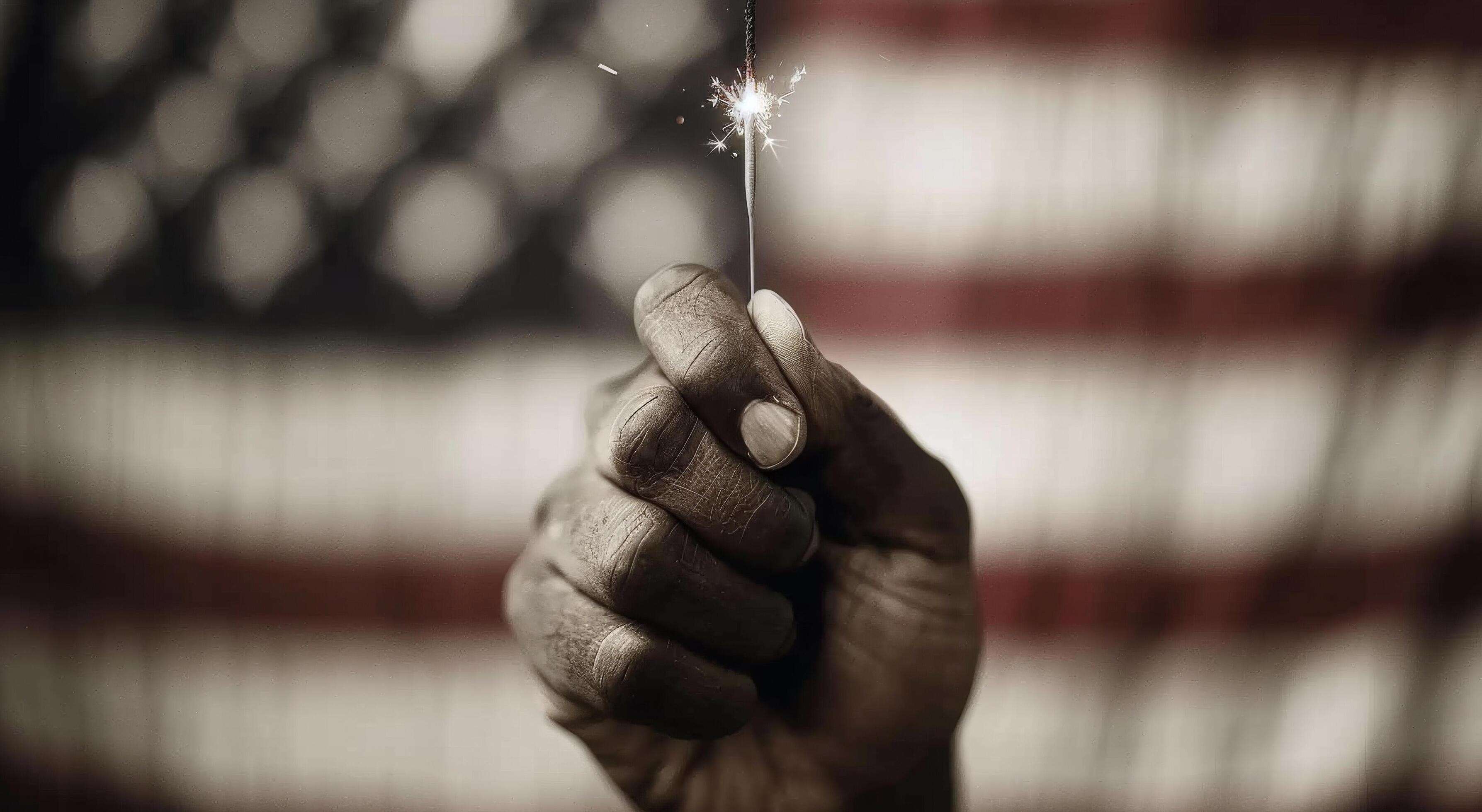 Hand Holding Sparkler Against Background of American Flag on Celebration Night Stock Free