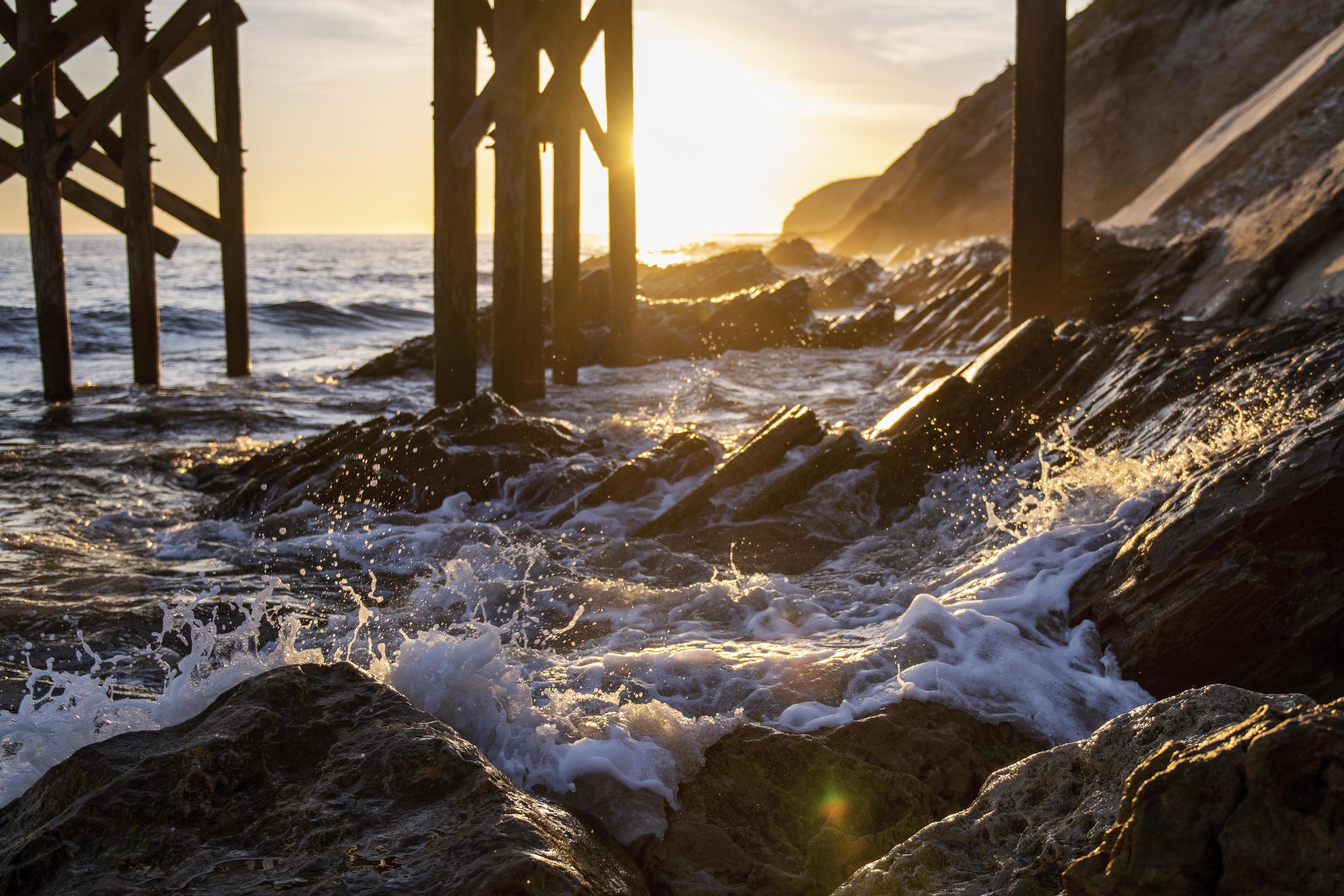 Waves crashing on shore under dock Stock Free