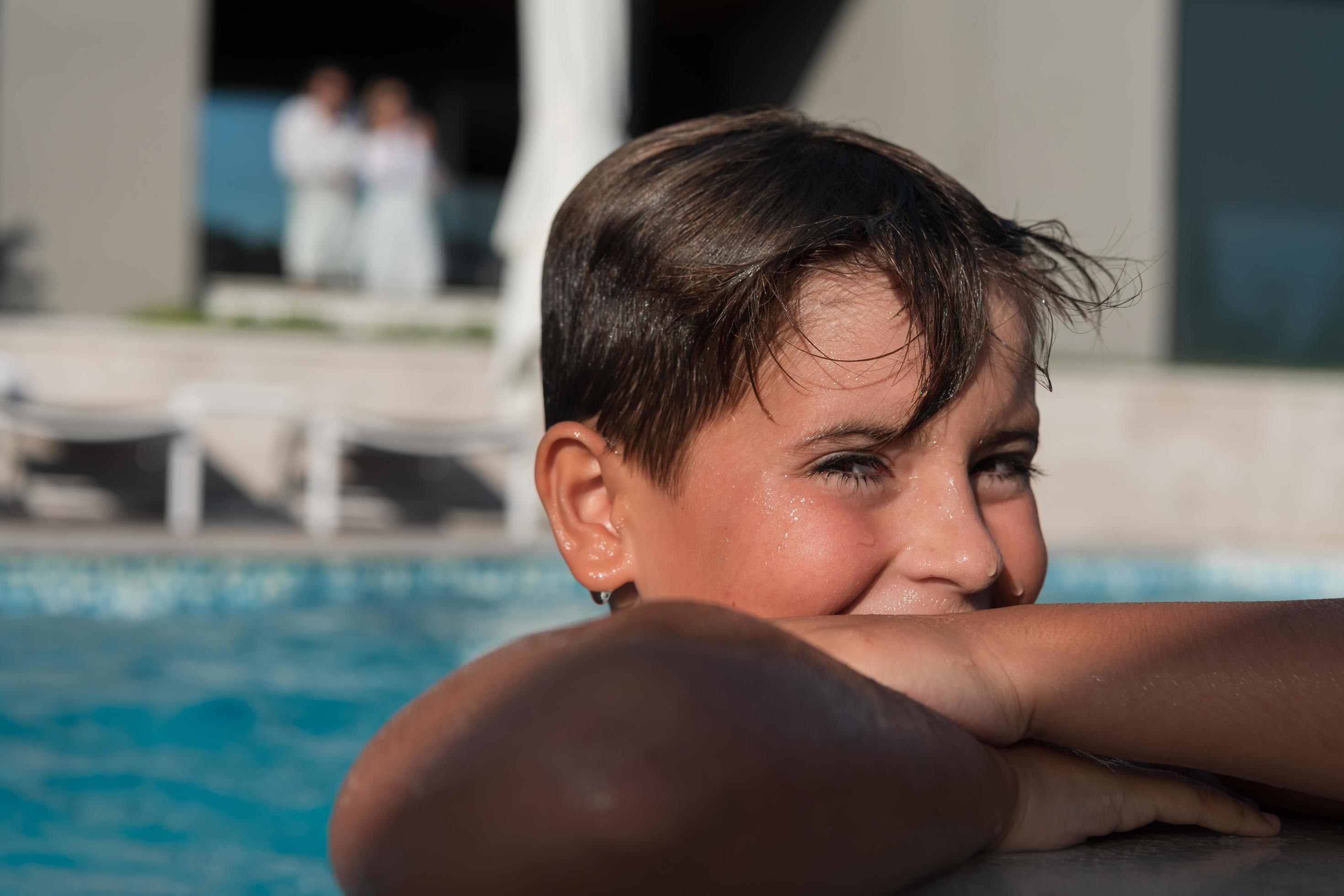 The boy enjoys a summer day swimming in the pool. The concept of a family vacation. Selective focus Stock Free