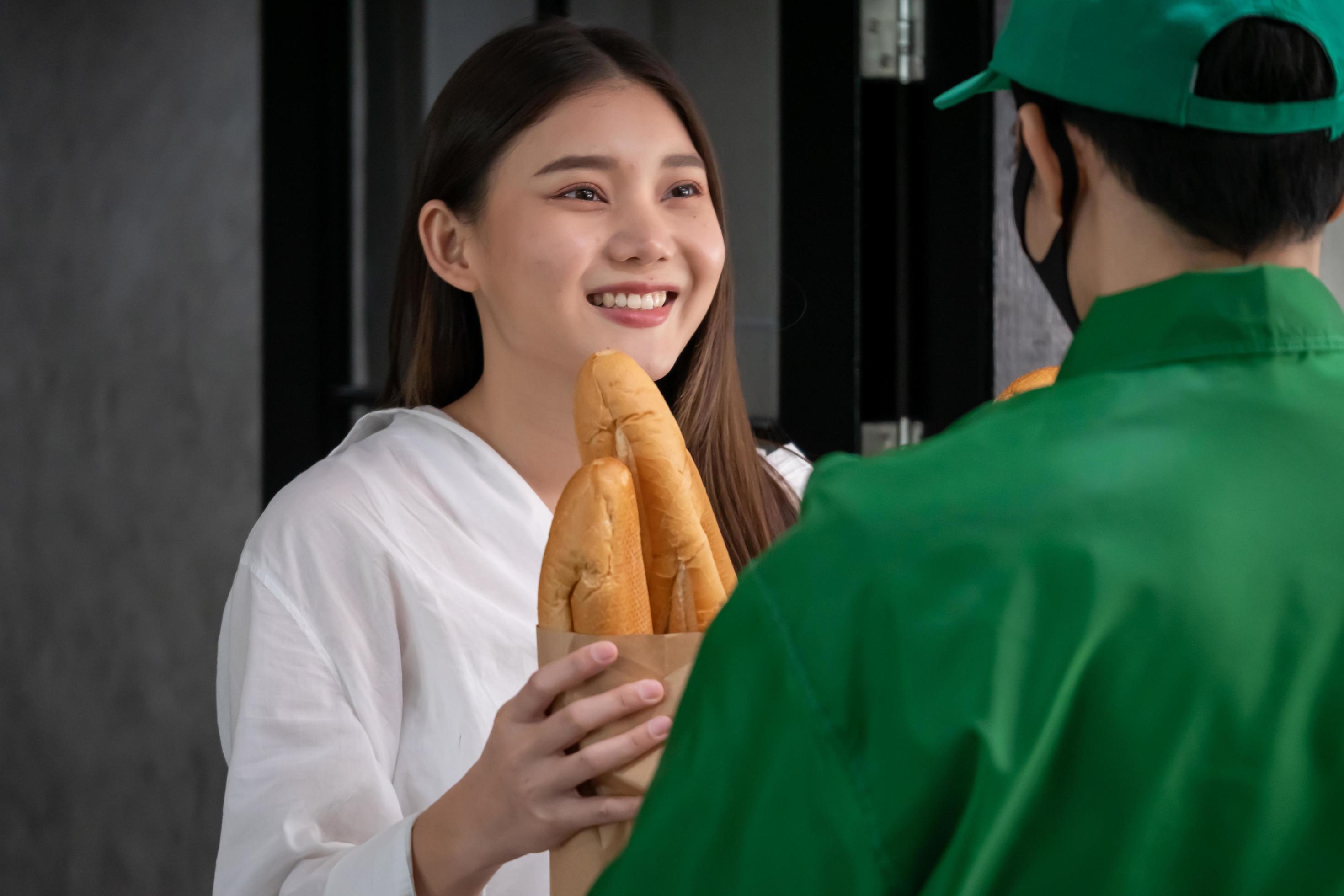 Happy woman recieving food from food deliveryman Stock Free