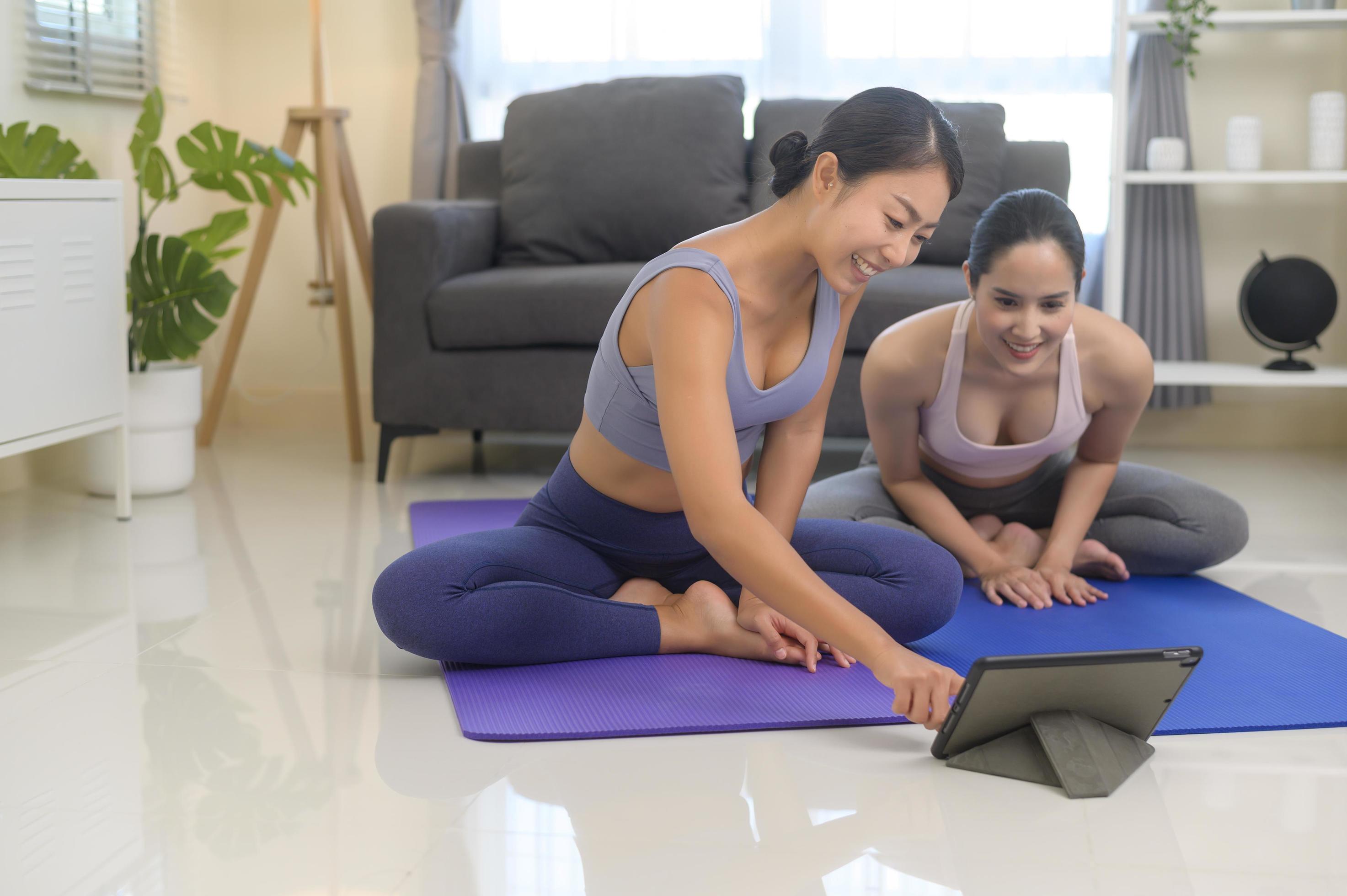 Fit young friend women practicing yoga at home via online class with professional instructor, sport and healthy lifestyle concept. Stock Free