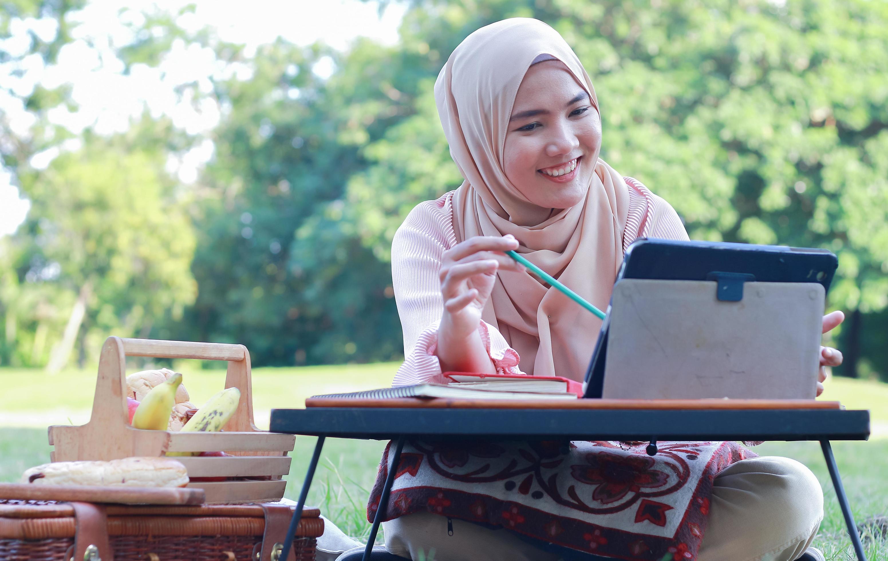 Beautiful Muslim girl sitting happily in the park. Muslim woman smiling in garden lawn. Lifestyle concept of a confident modern woman Stock Free