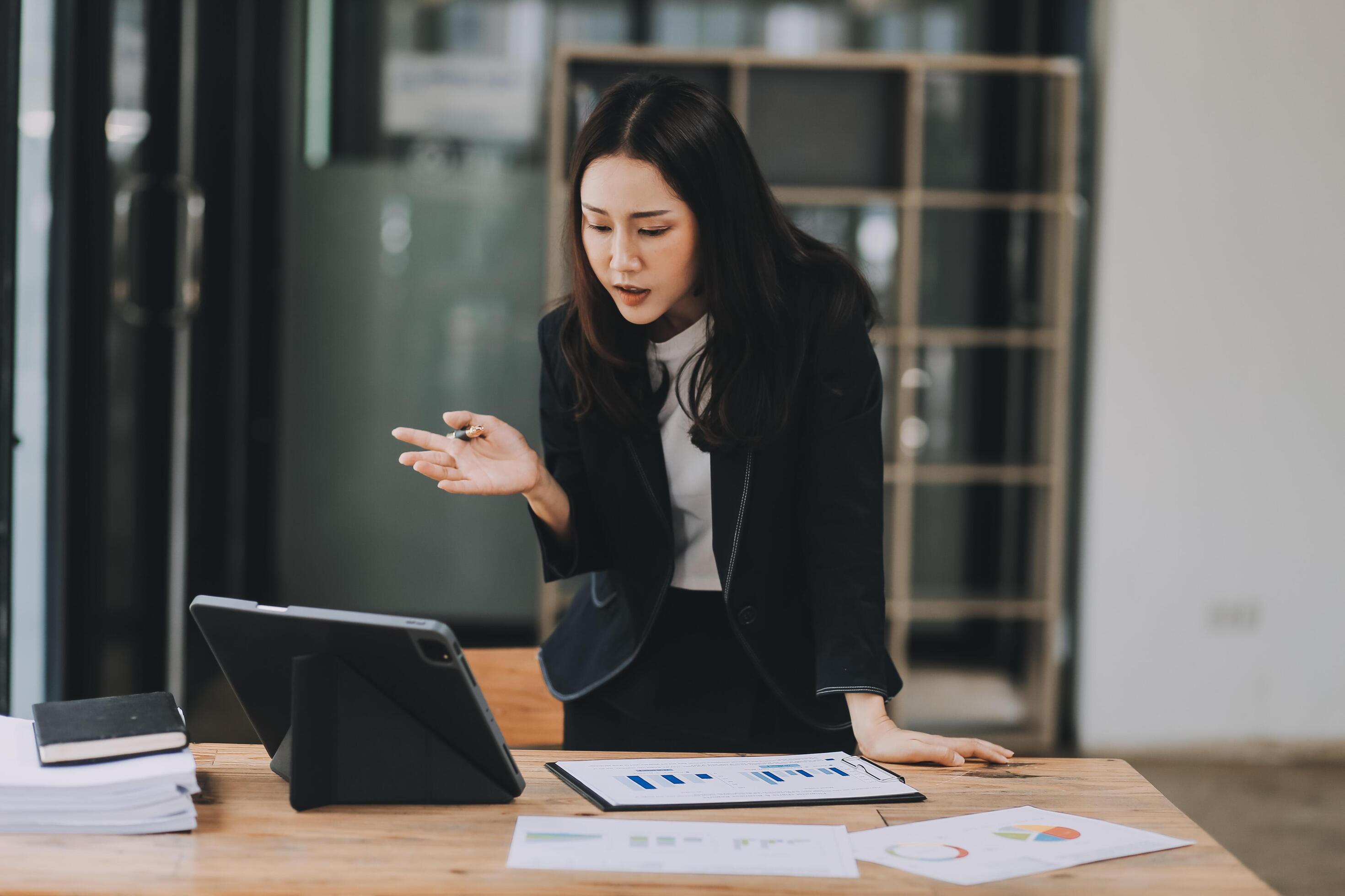 Pretty young Asian businesswoman working on laptop and taking notes In office. Stock Free