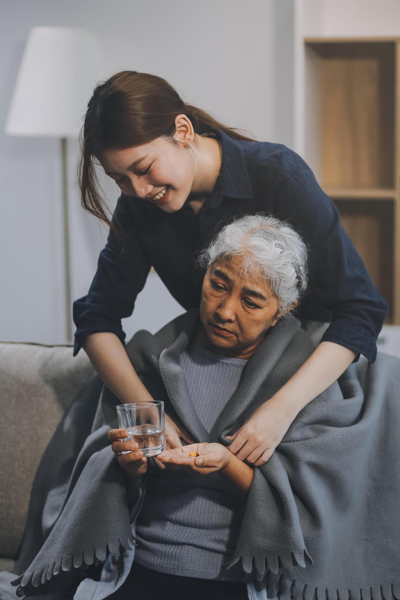 happy family Granddaughter takes care of her grandmother with warm cloths sitting on the sofa. Stock Free