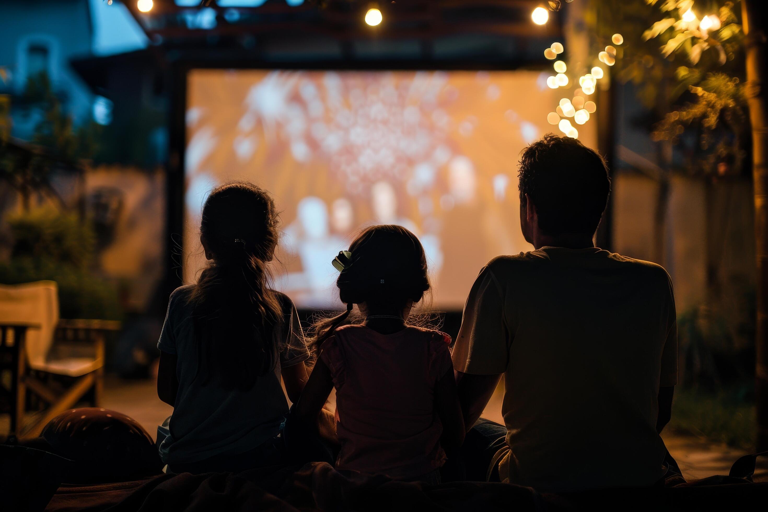 people are sitting in lawn chairs in front of a large screen Stock Free