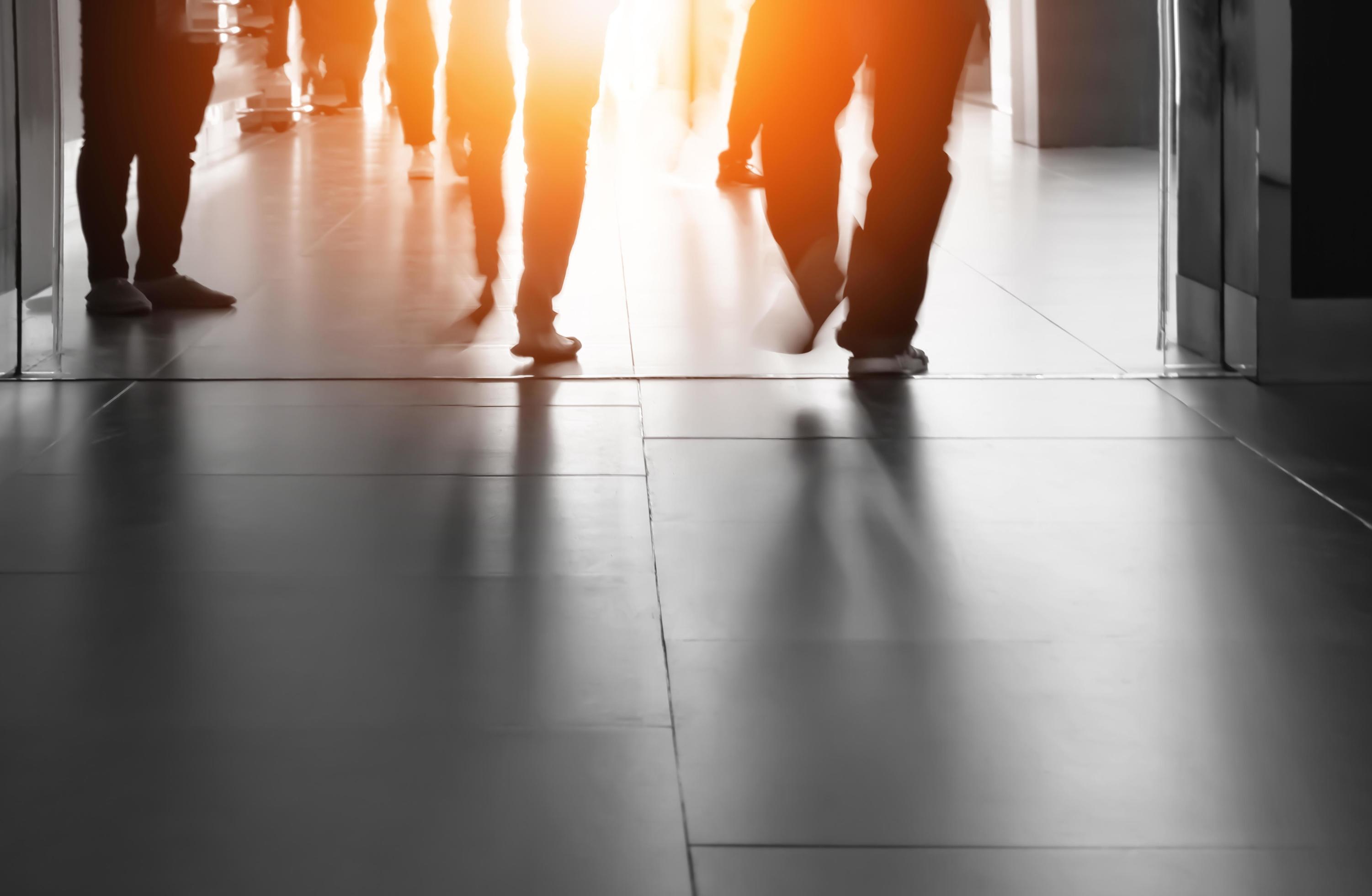 Silhouette motion blur of people legs are walking into the building with flare light and shadow on surface of passageway, city lifestyles Stock Free