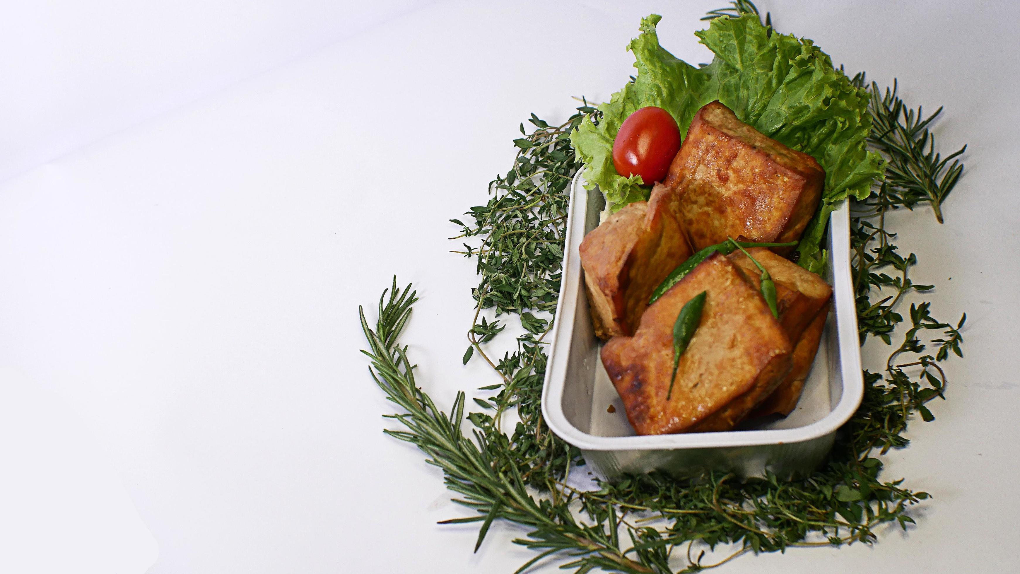 Fried tofu, small tomatoes and green chilies along with lettuce in one aluminum container, Indonesian street food on a white background Stock Free