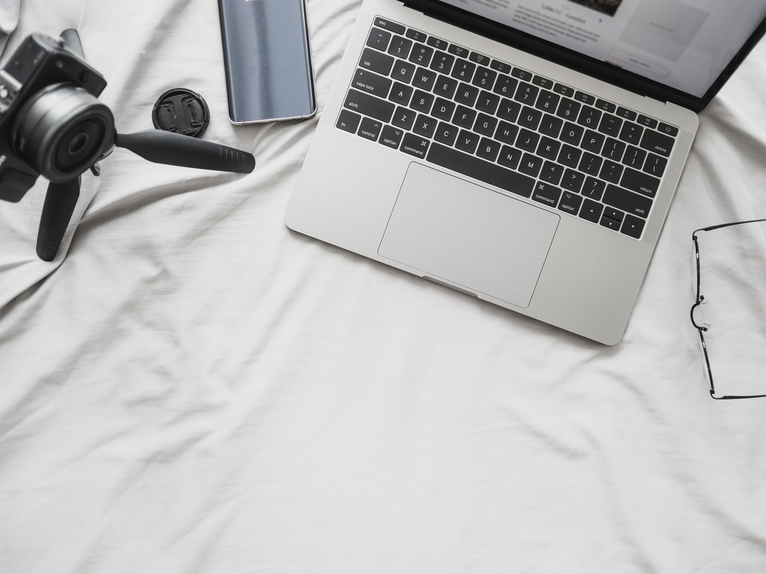 Above view of laptop computer camera and smartphone on bed. Concept of blogger and working at home digital lifestyle Stock Free