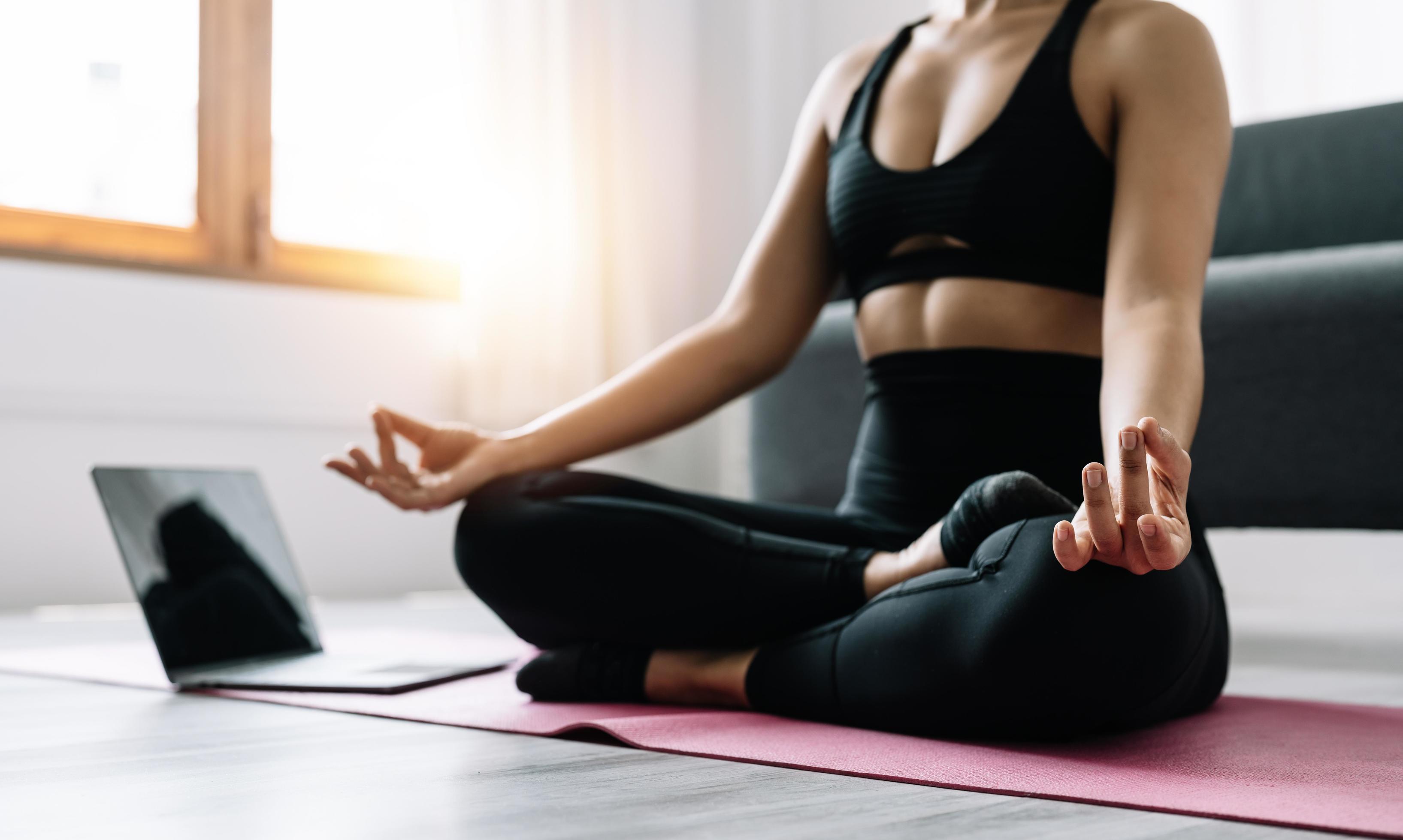 Young woman exercising, asian woman practicing meditation indoors from laptop, Yoga and Healthy lifestyle concept. Stock Free