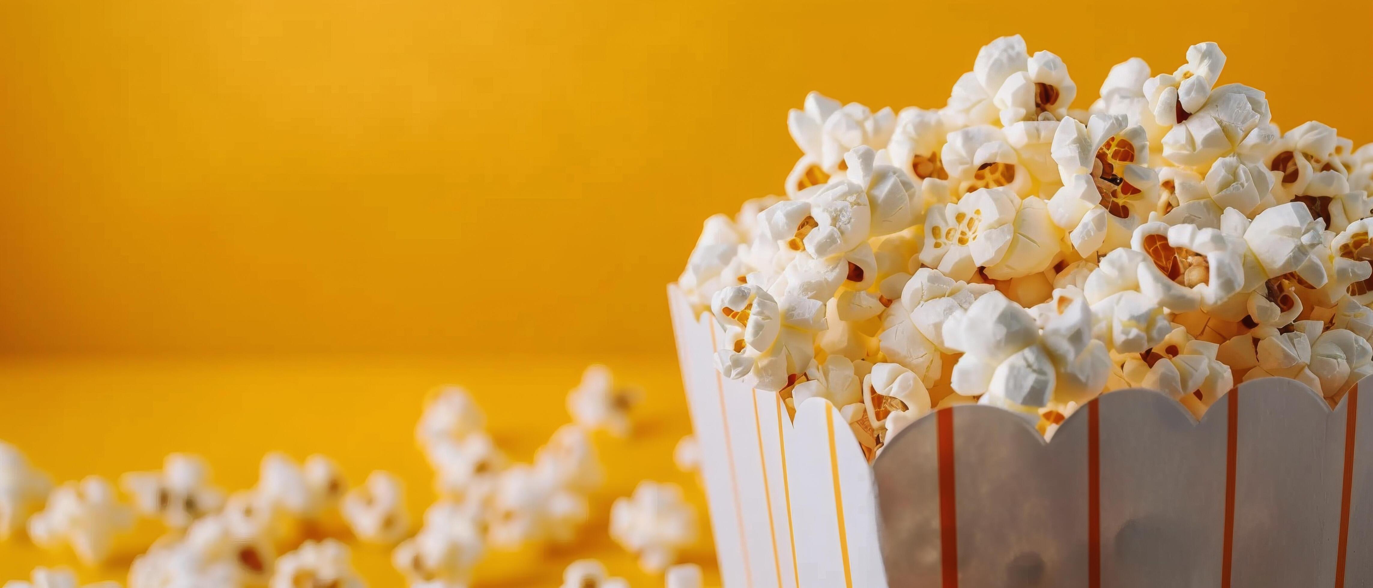 Freshly Popped Popcorn in a Striped Box Against a Bright Yellow Background Stock Free