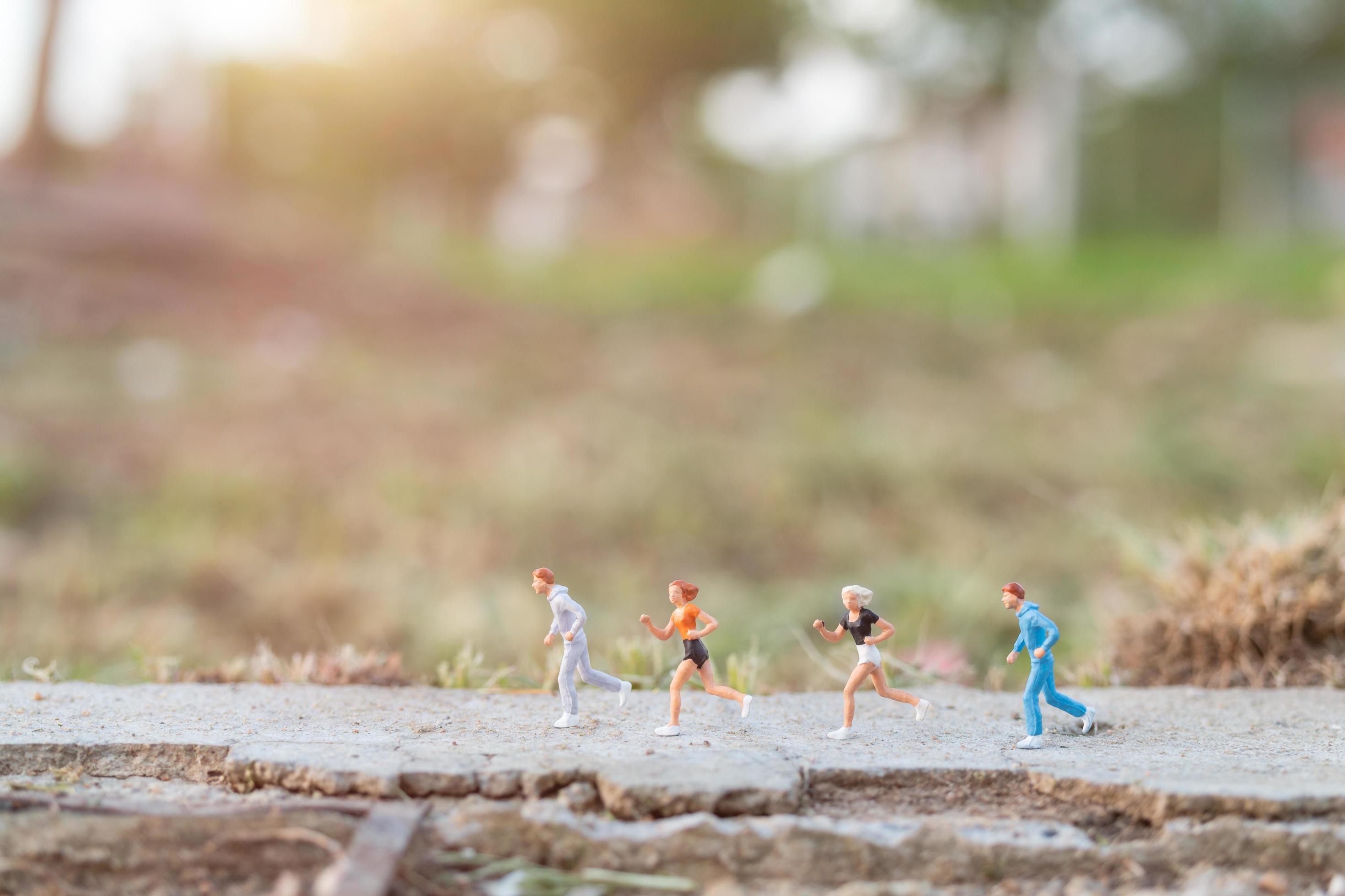 Miniature people running on a road with a nature background, health and lifestyle concept Stock Free