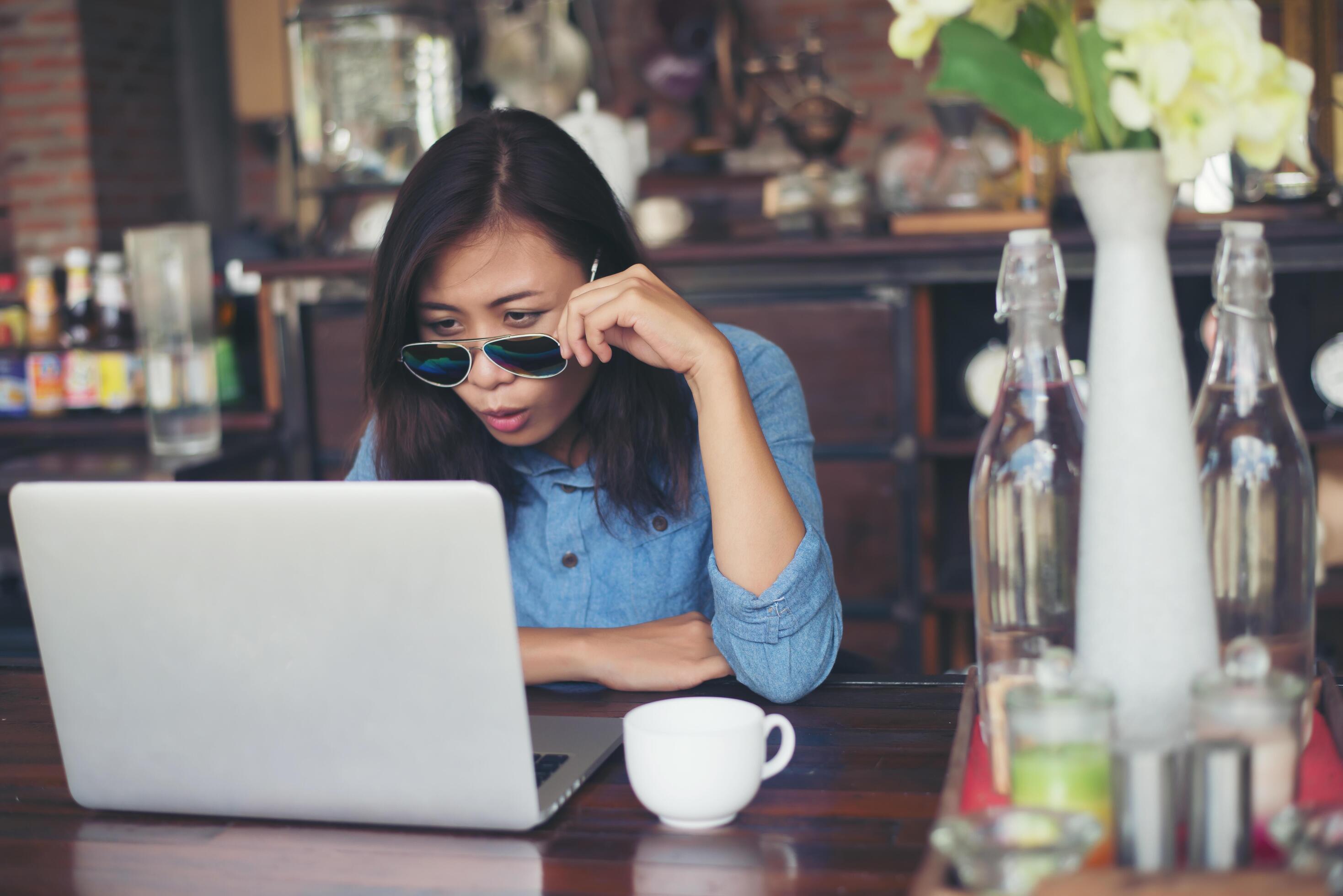 Pretty young hipster woman sitting in a cafe with her laptop, looked away and smiled happy, Relaxing with holiday, Woman lifestyle concept. Stock Free