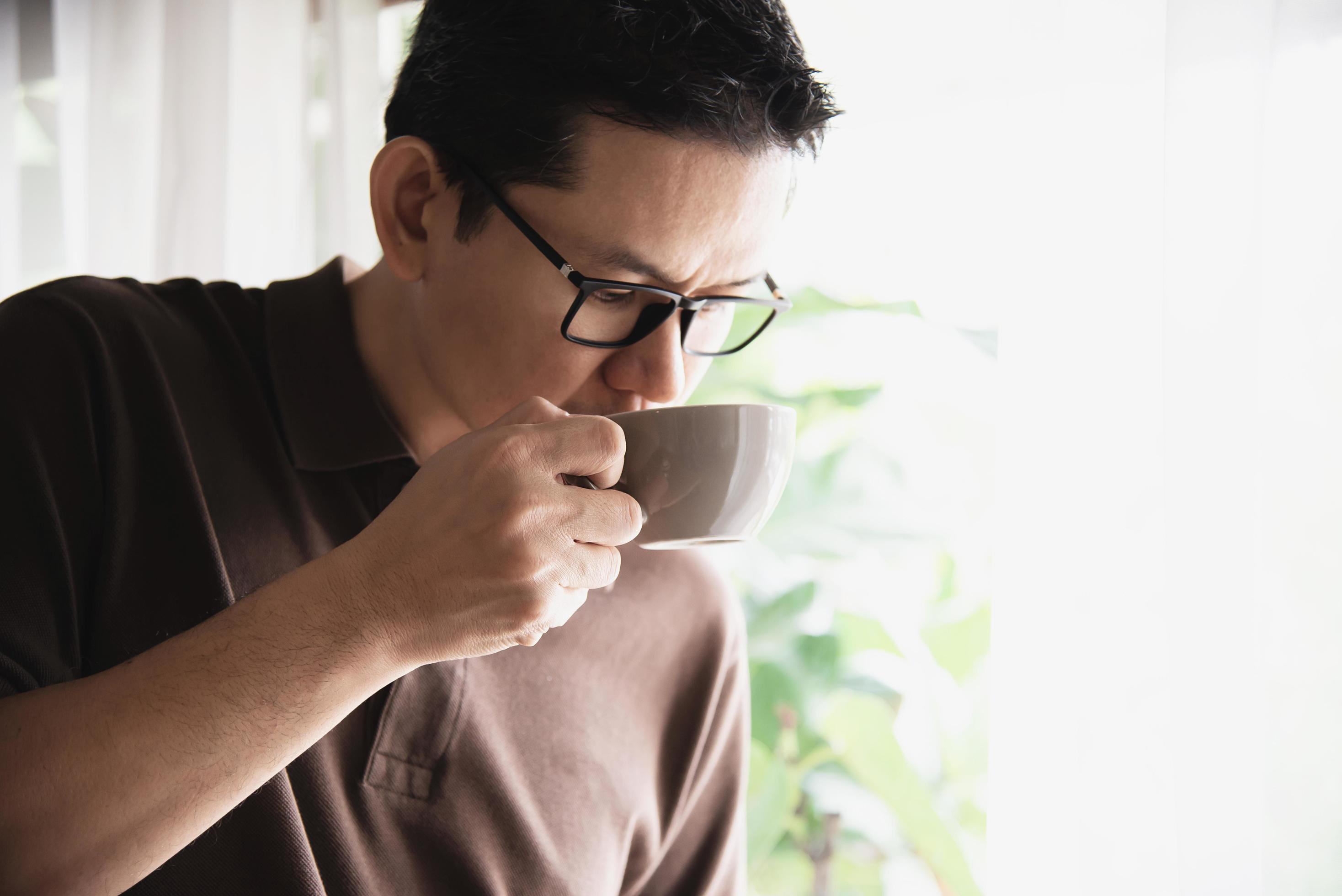 Relax Asian man drink coffee and read book in a modern style coffee shop – people with coffee cup easy lifestyle concept Stock Free