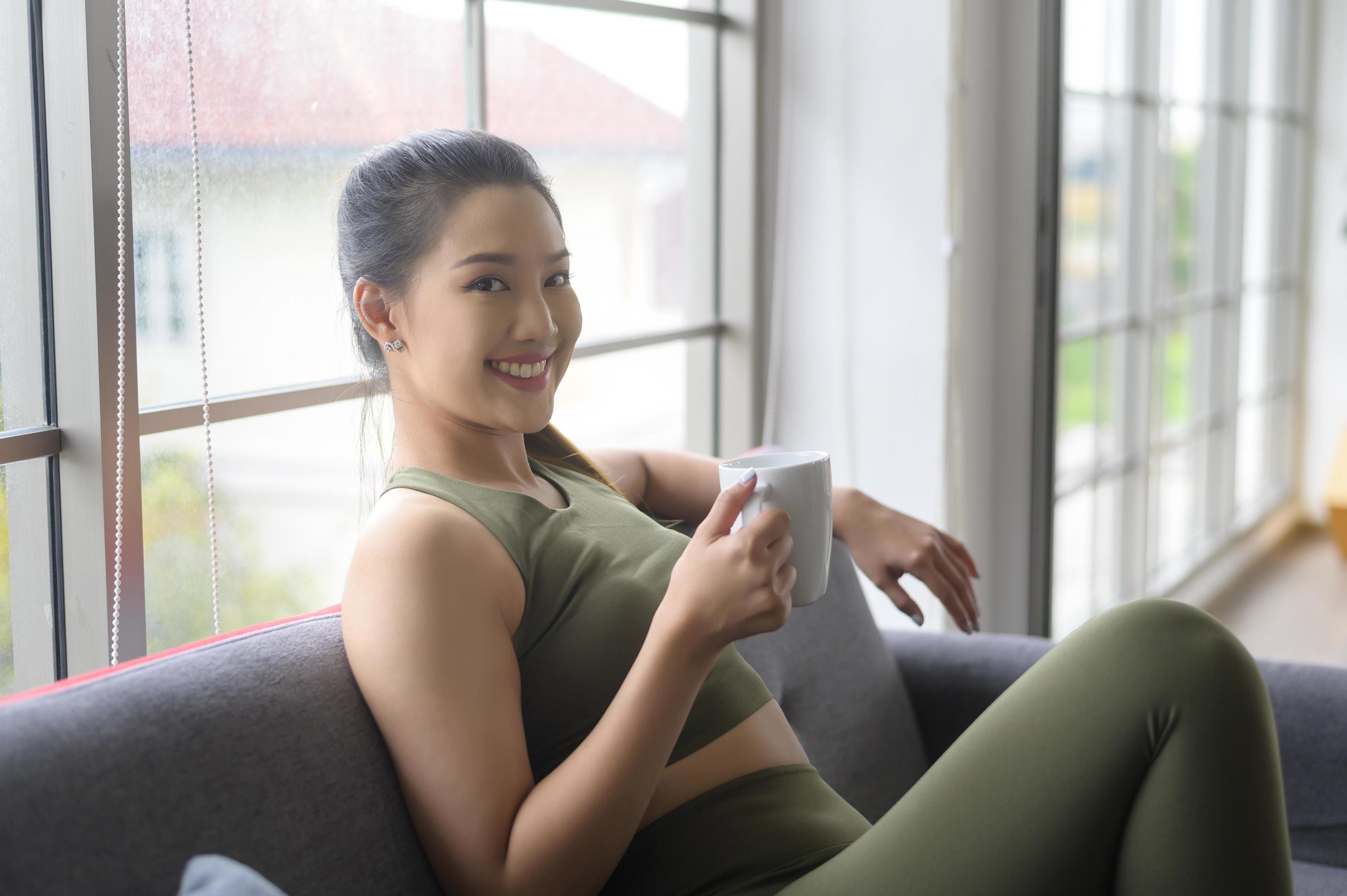 Young fitness woman in sportswear having a cup of coffee after exercising at home, Healthy and Lifestyles. Stock Free