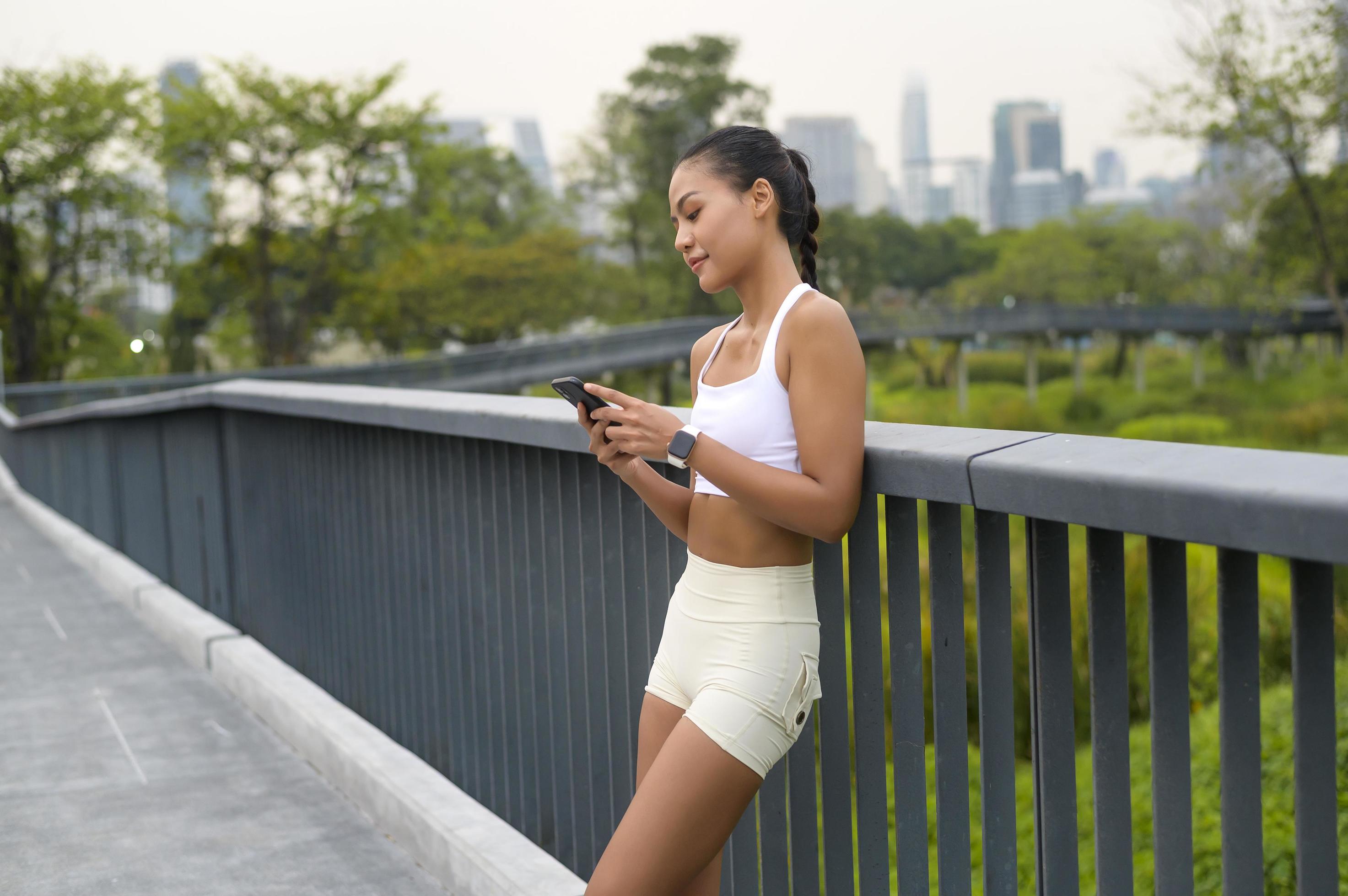 Young fitness woman in sportswear using smart phone while exercising in city park, Healthy and Lifestyles. Stock Free