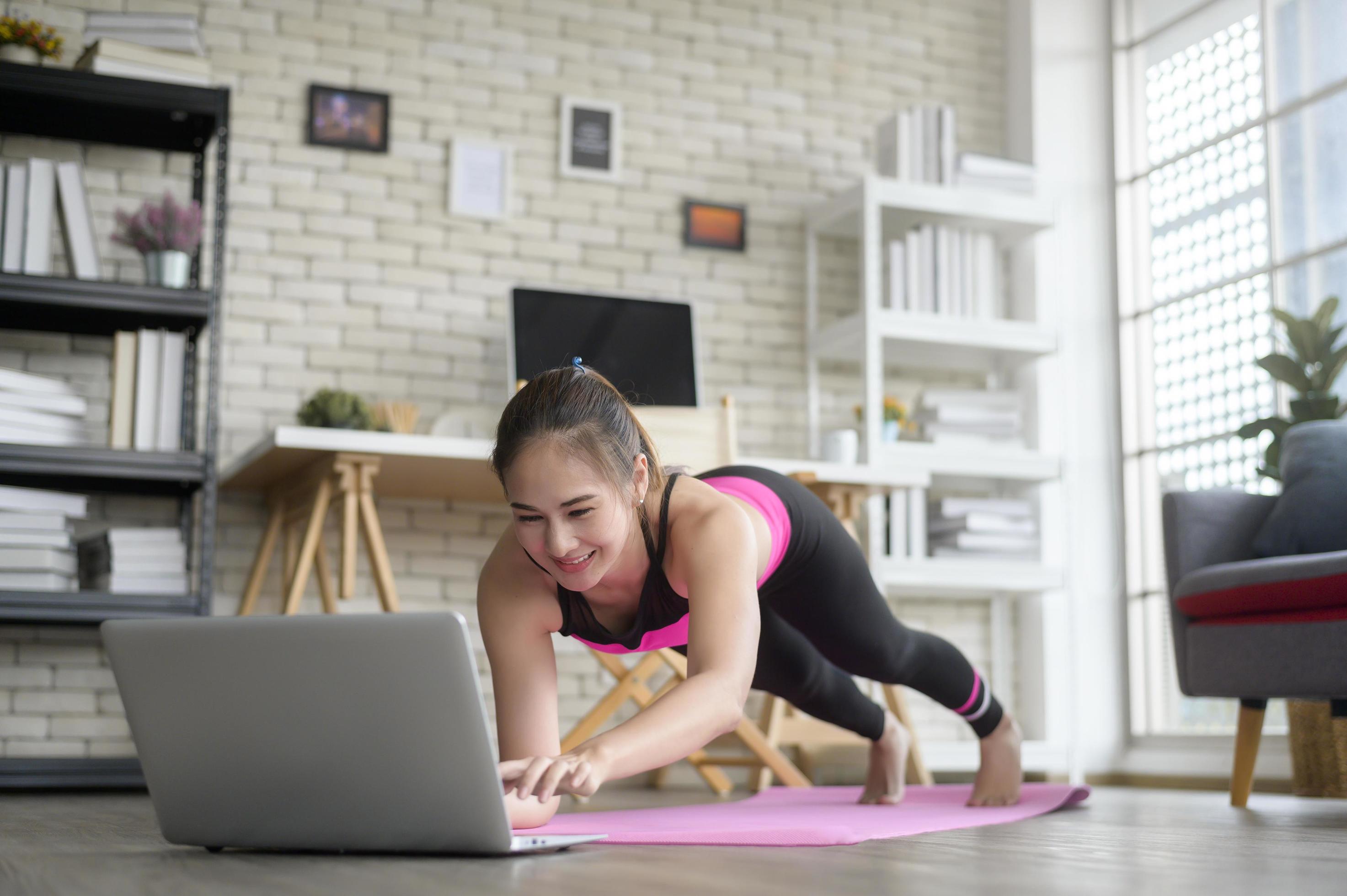 Fit young woman practicing yoga at home via online class with professional instructor, sport and healthy lifestyle concept. Stock Free