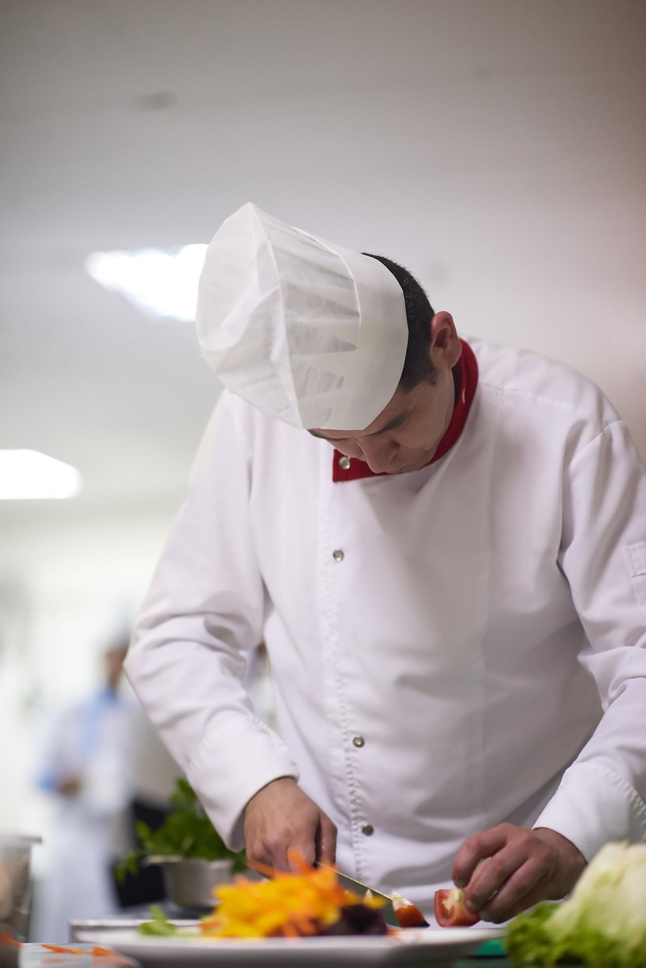 chef in hotel kitchen preparing and decorating food Stock Free