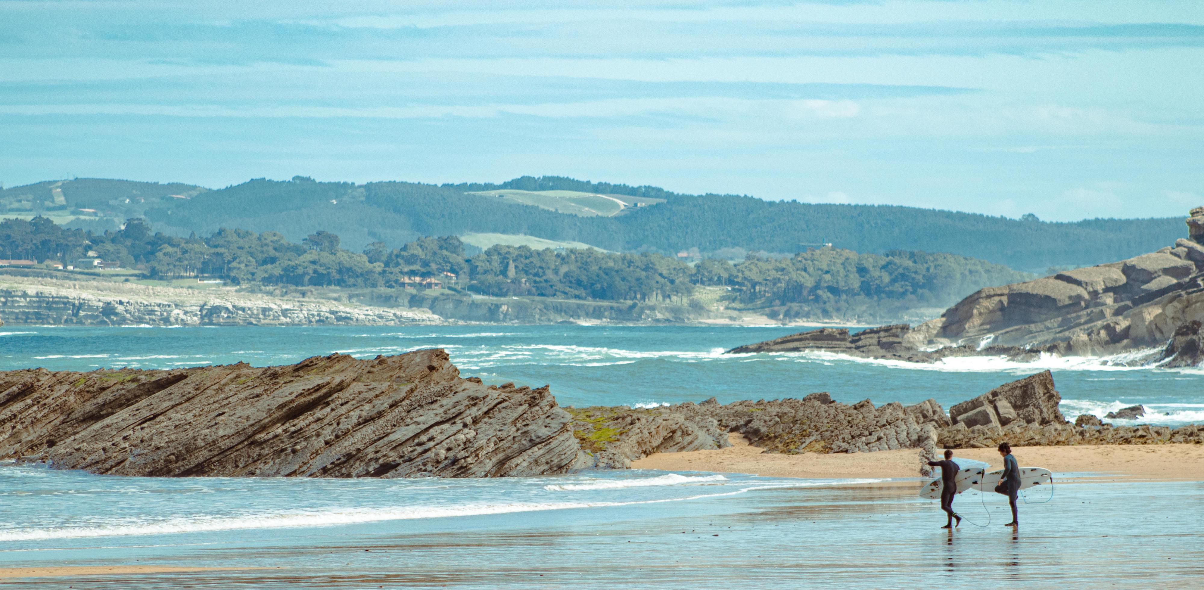 Couple of surfers walking on the beach. Going to do some surfing Stock Free